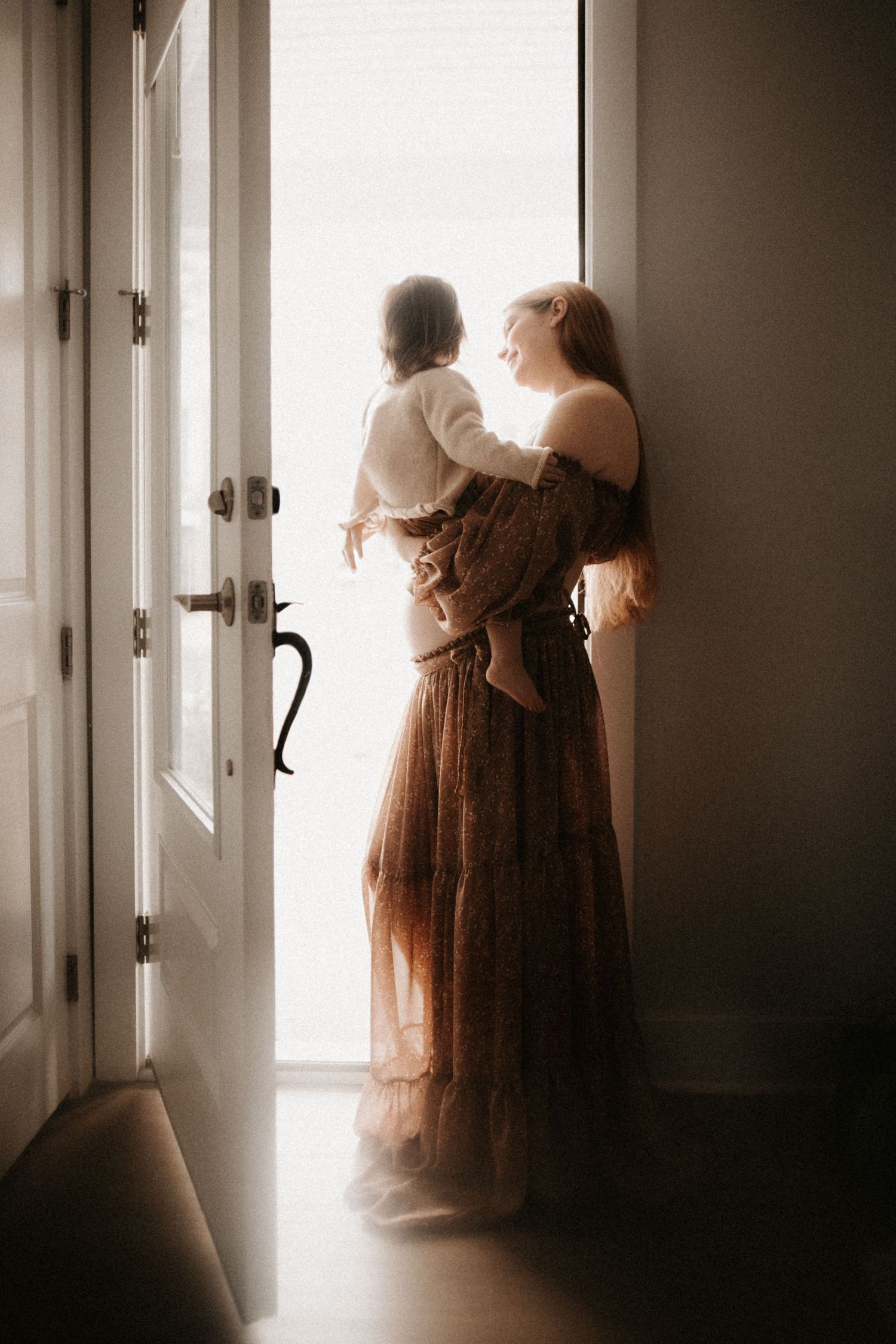 Atmospheric silhouette by doorway in vintage dress creating dreamy, ethereal mood.