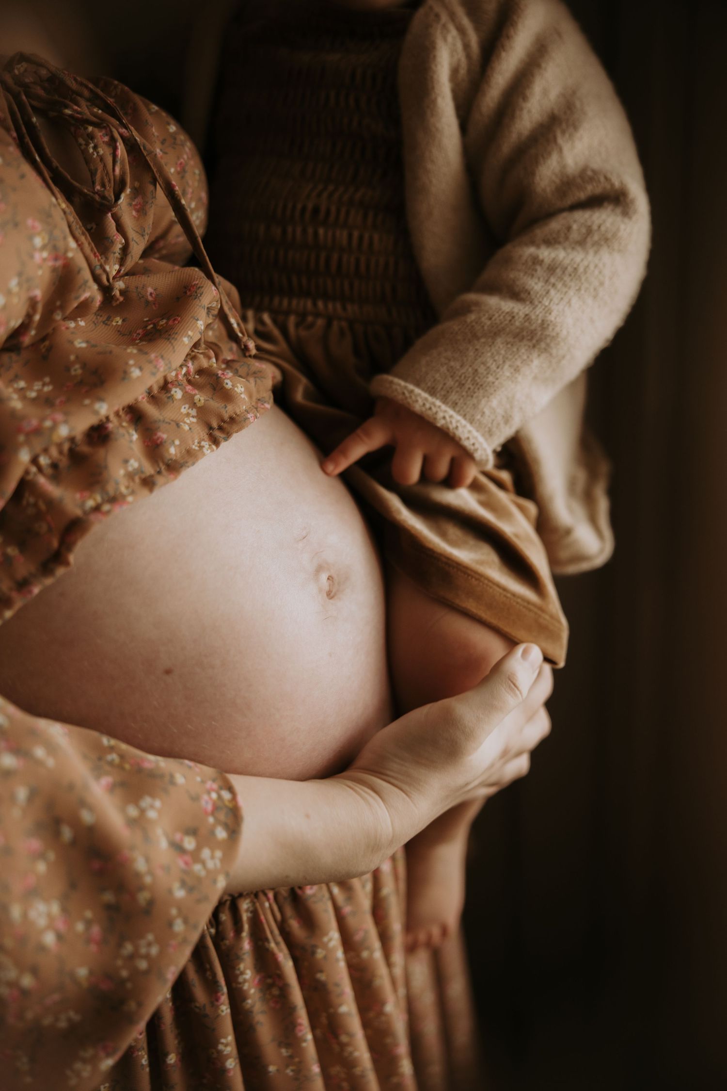 Artistic maternity photo series showing pregnant belly in warm sepia tones with delicate lace details.
