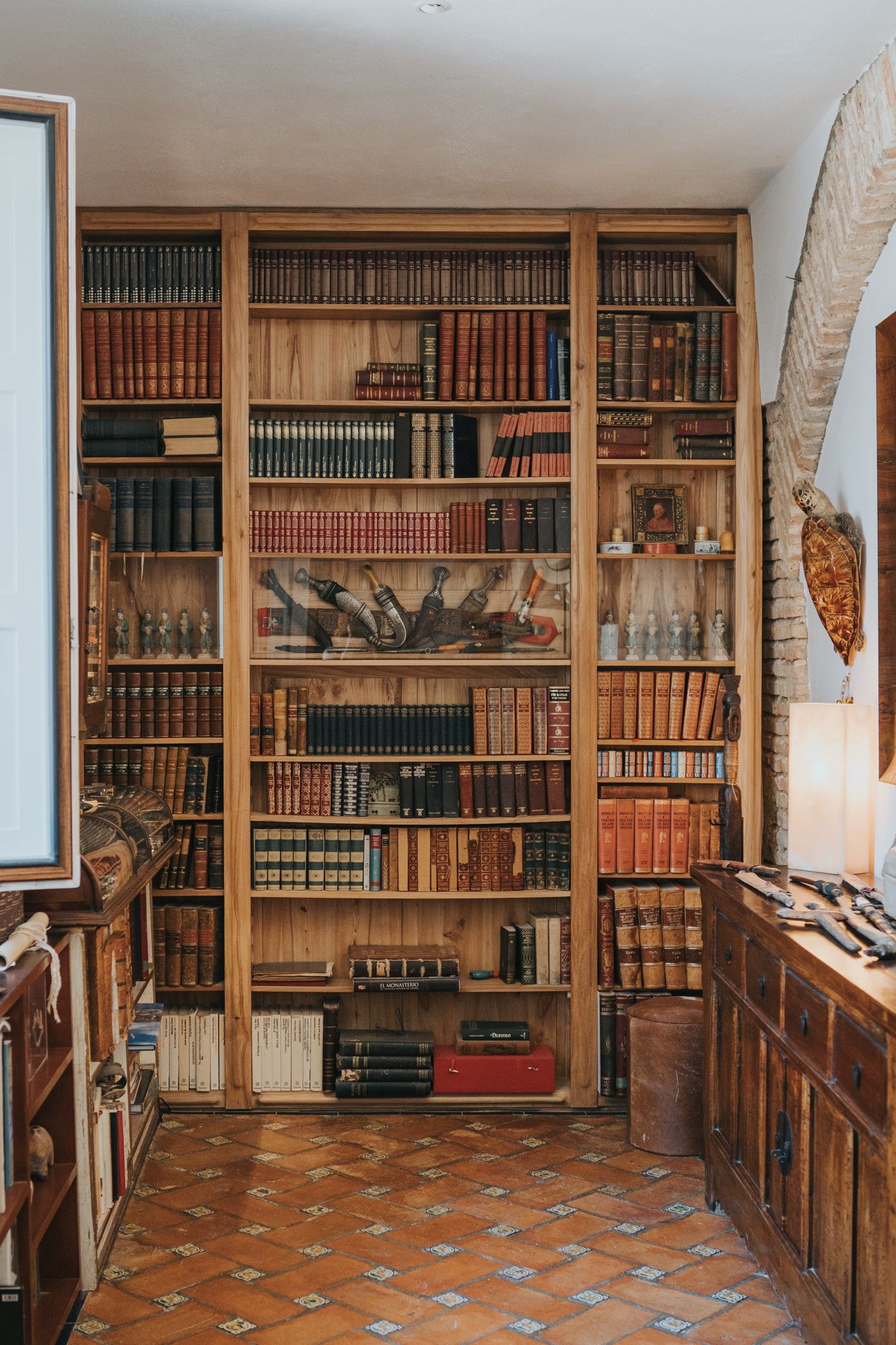 Classic wooden library with floor-to-ceiling bookshelves filled with vintage leather-bound books.