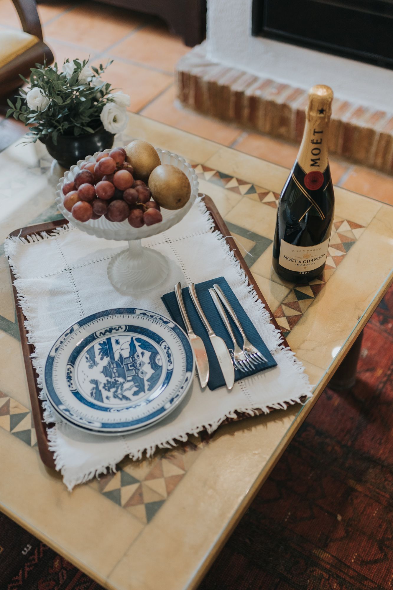 Table setting with Moet champagne, fruit, blue china plate, and white floral arrangement.