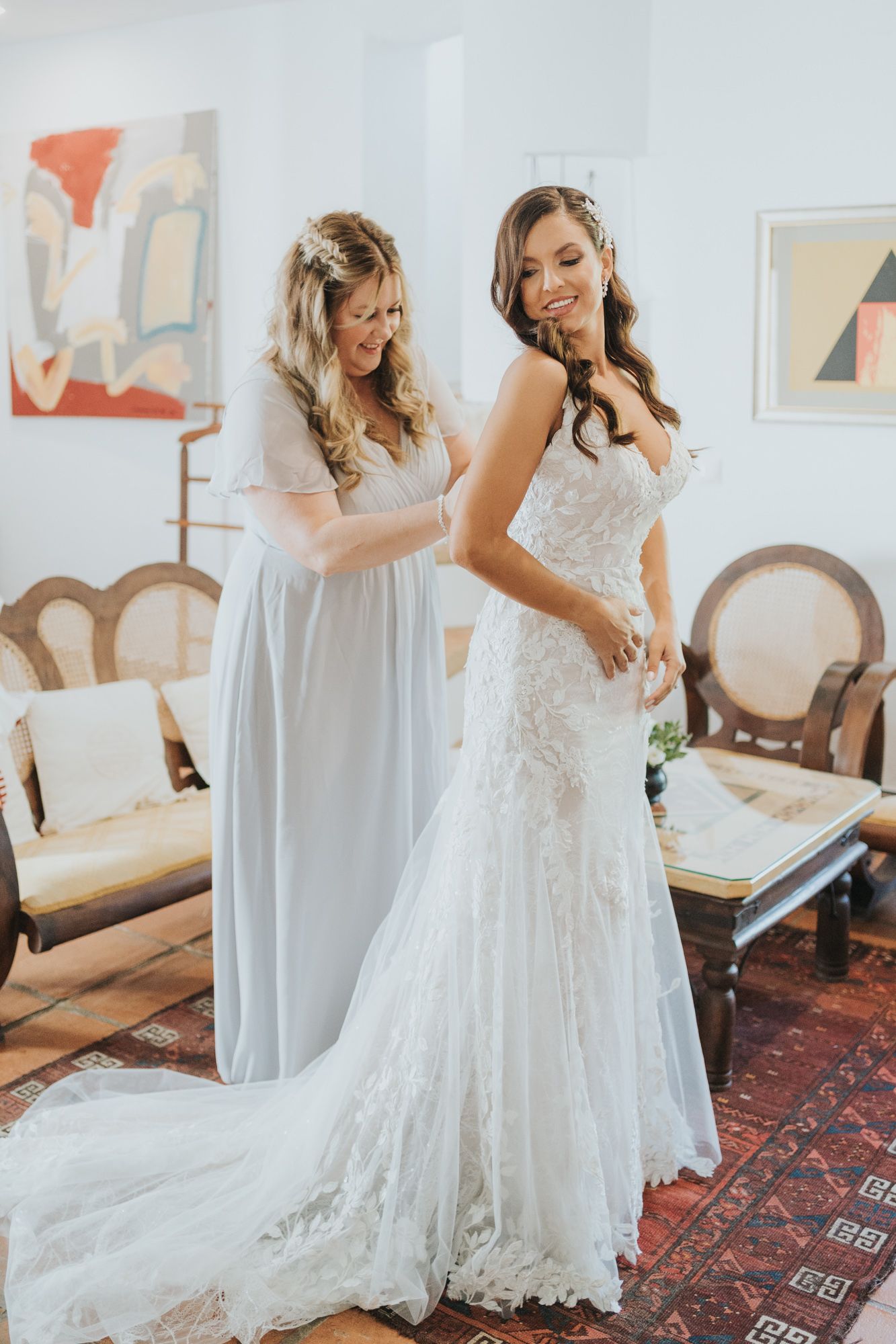 Elegant wedding dress fitting in a vintage-styled room with antique furniture.