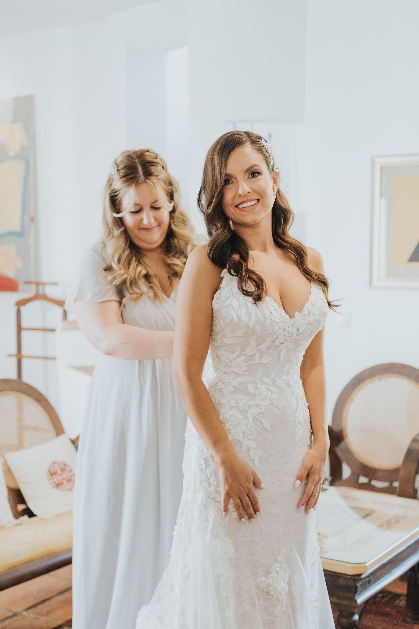 Beautiful lace wedding gown being fitted in an elegant room with classic decor.