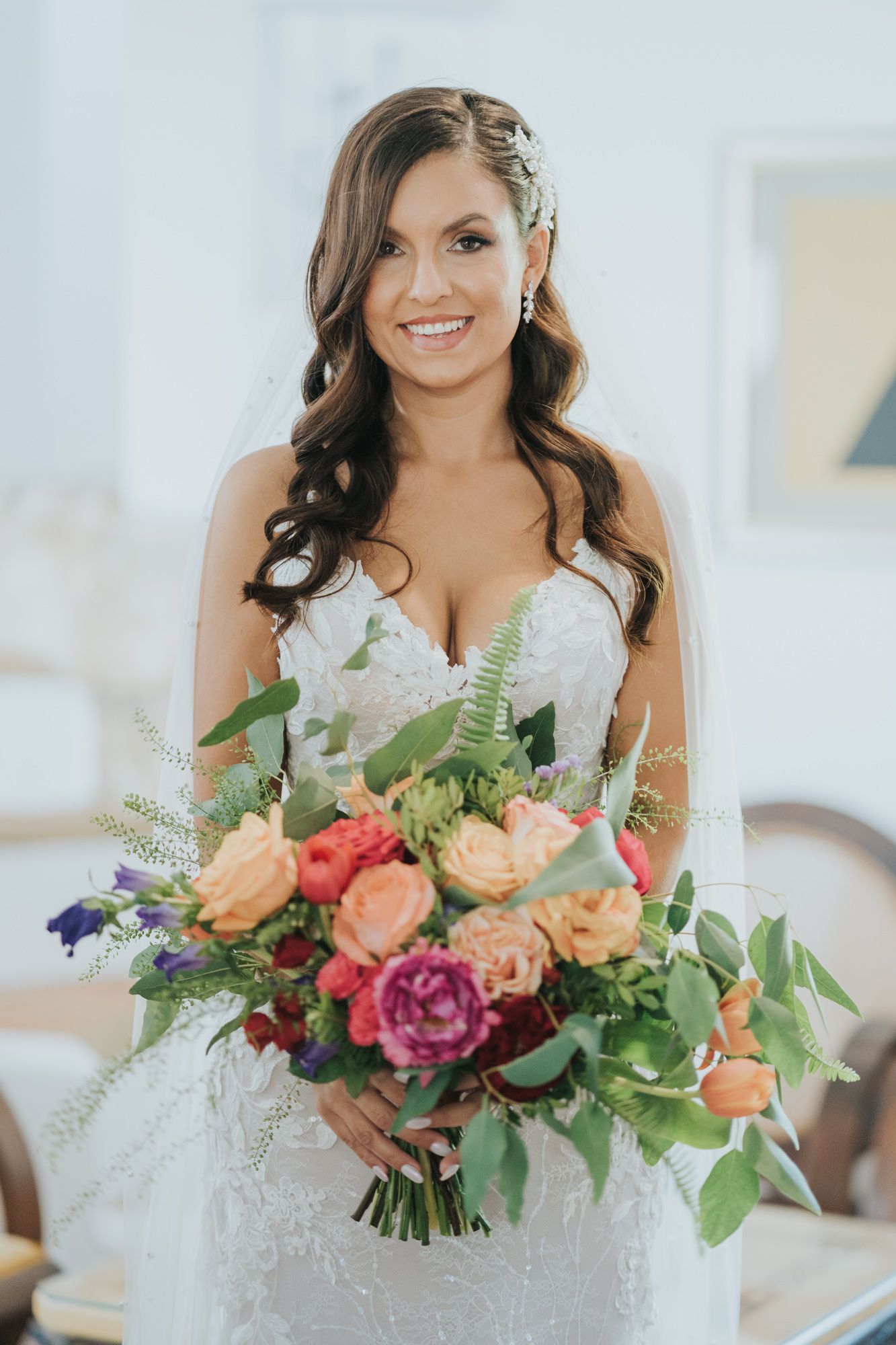 A bridal portrait showcasing a stunning bouquet with coral, purple and peach roses with greenery accents.