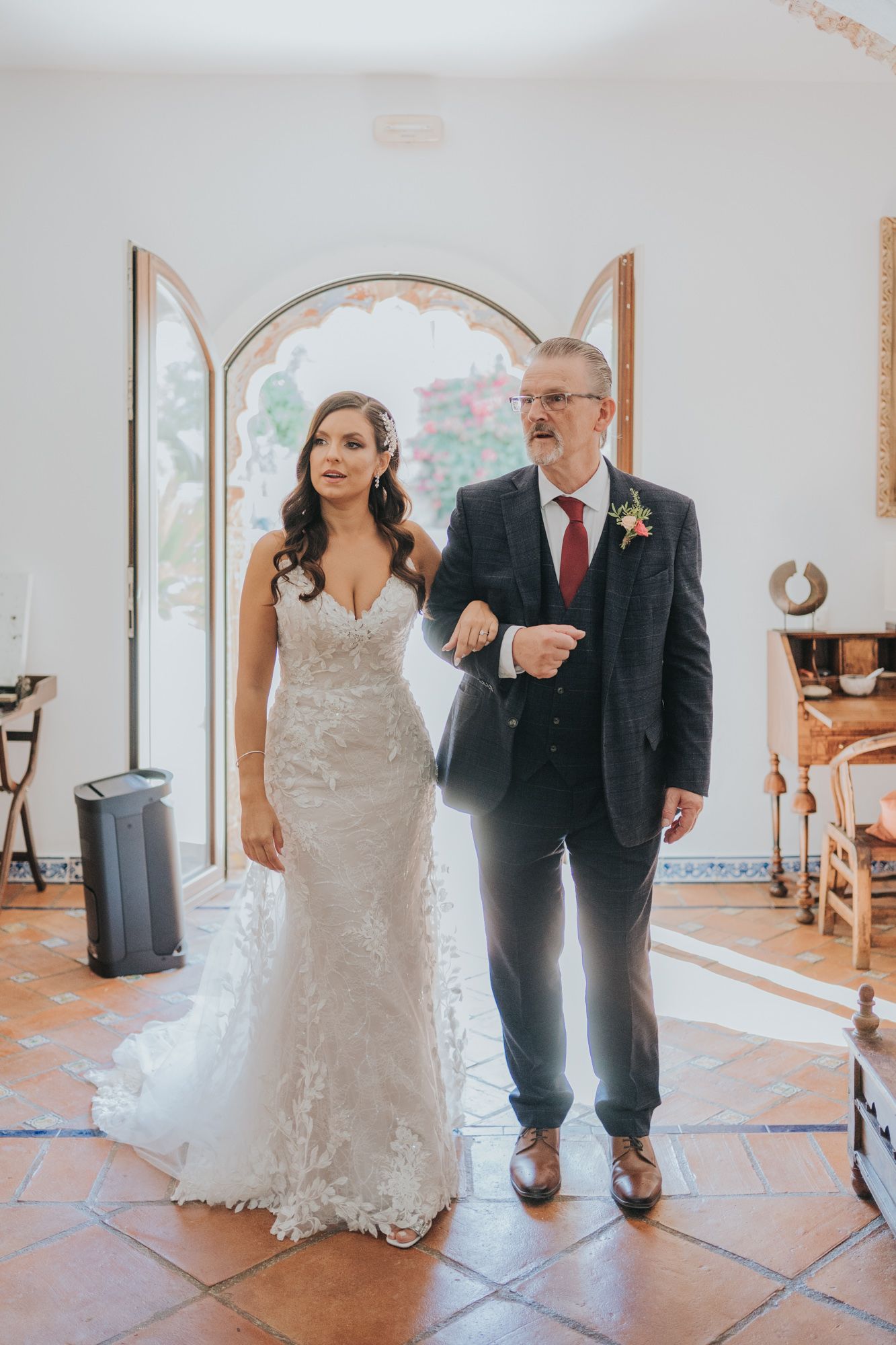 A beautiful wedding ceremony in an elegant room with arched windows and terracotta floors.