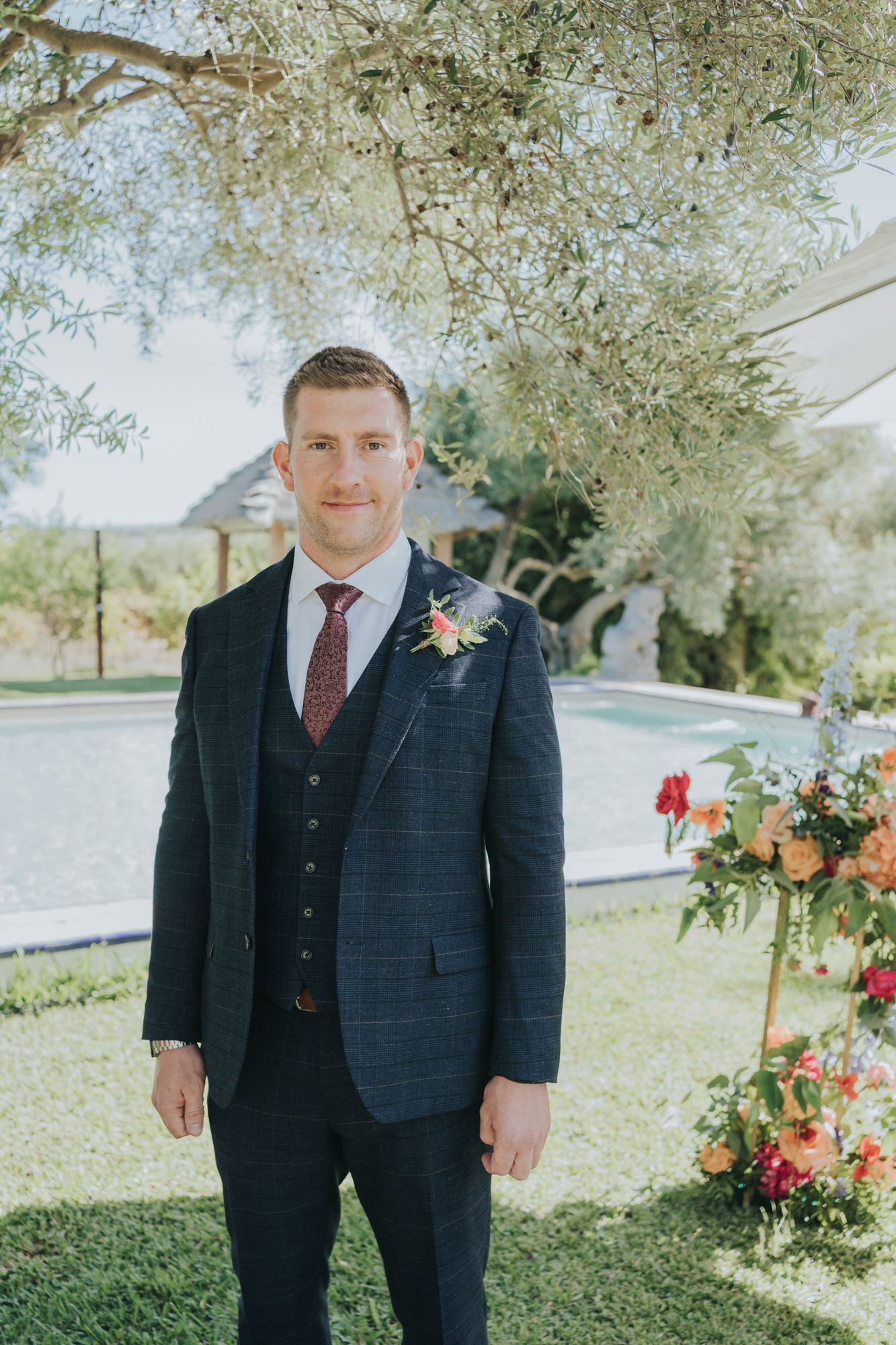 Wedding attire and floral boutonniere against a spring garden backdrop.