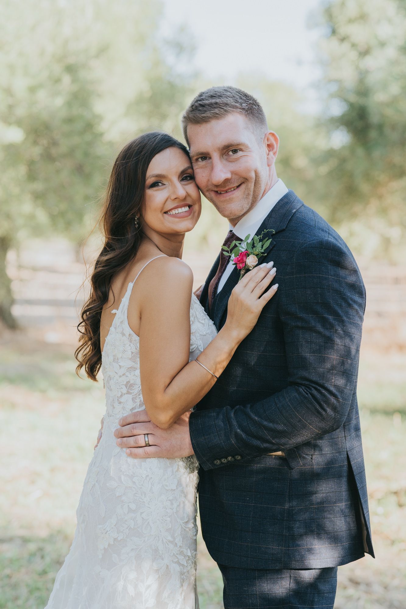 Romantic outdoor wedding portrait amid blooming trees and natural light.