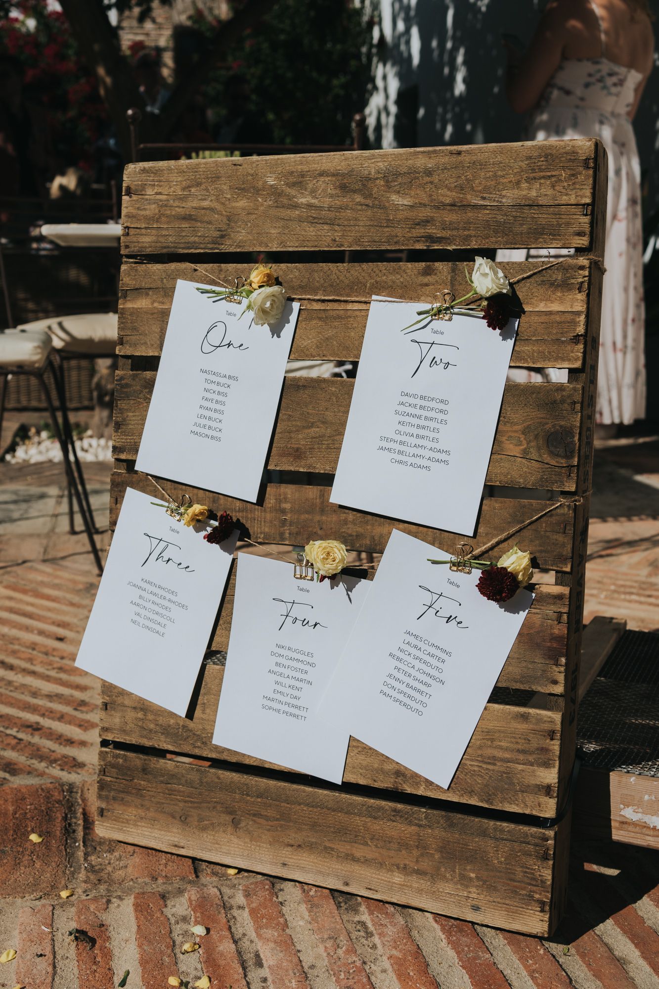 Wedding seating chart displayed on rustic wooden boards with dried flowers as decorative accents.