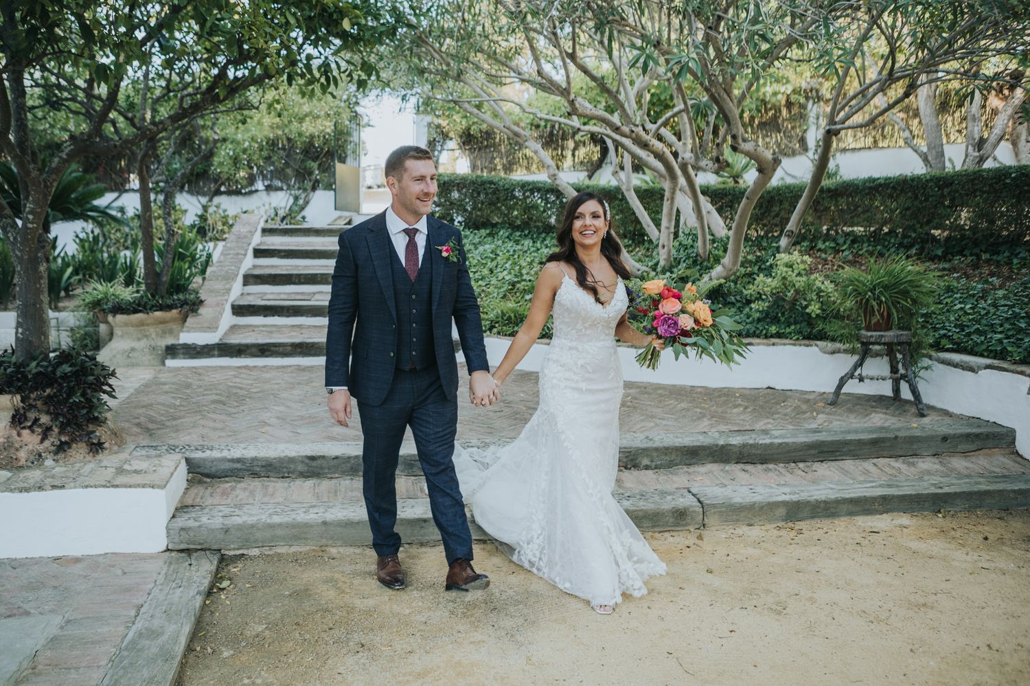 A couple poses on outdoor garden steps during their wedding day photoshoot.