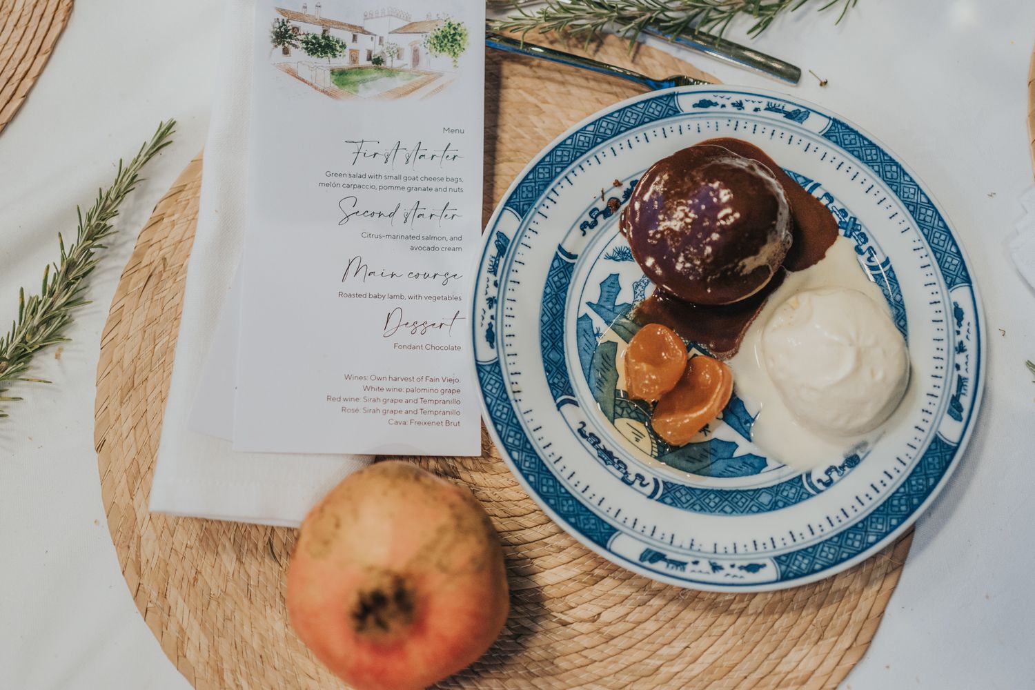 A decorative plate with chocolate dessert and ice cream alongside a menu card and apple on woven placemat.