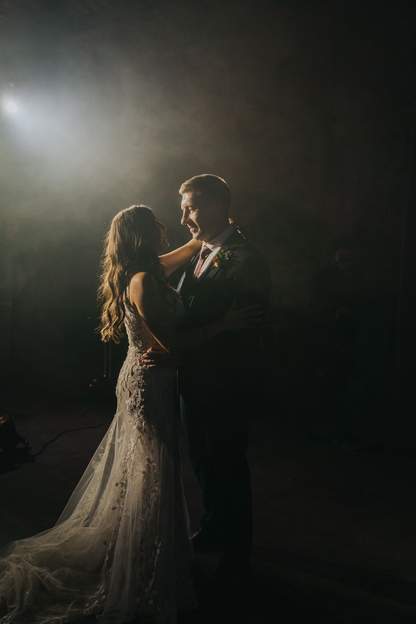 Romantic silhouette of a couple dancing in dramatic backlit spotlight at their wedding.