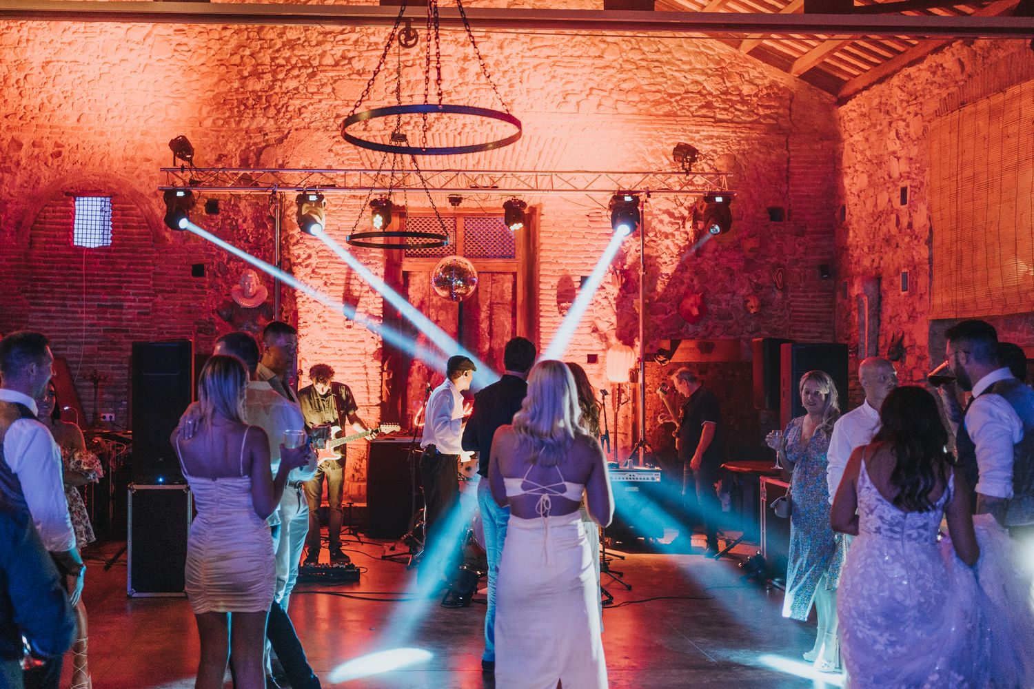 Dance floor filled with party guests under blue and red lighting in a brick-walled event space.