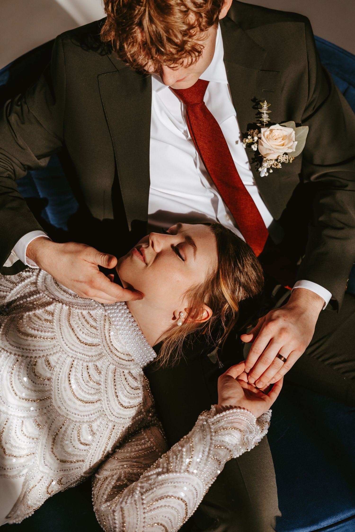 Romantic wedding portrait showing couple in formal attire on blue furniture.