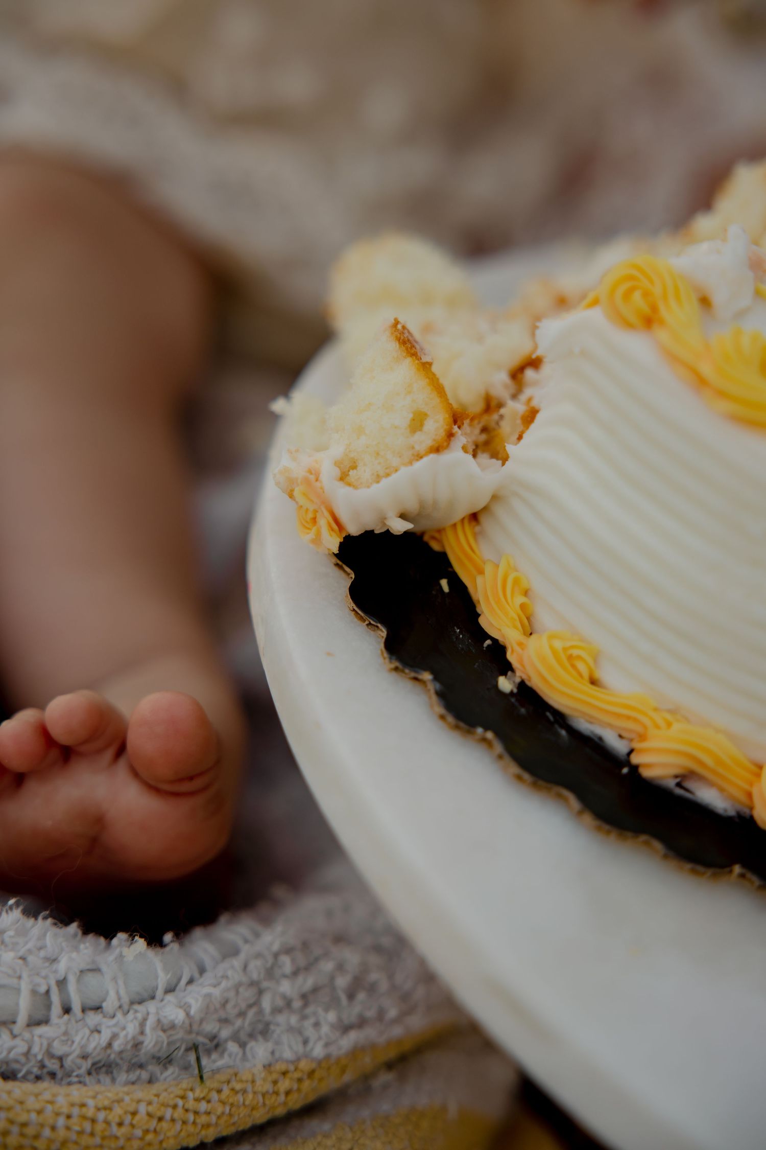 Close-up of a decorated white and yellow cake with smashed portions.