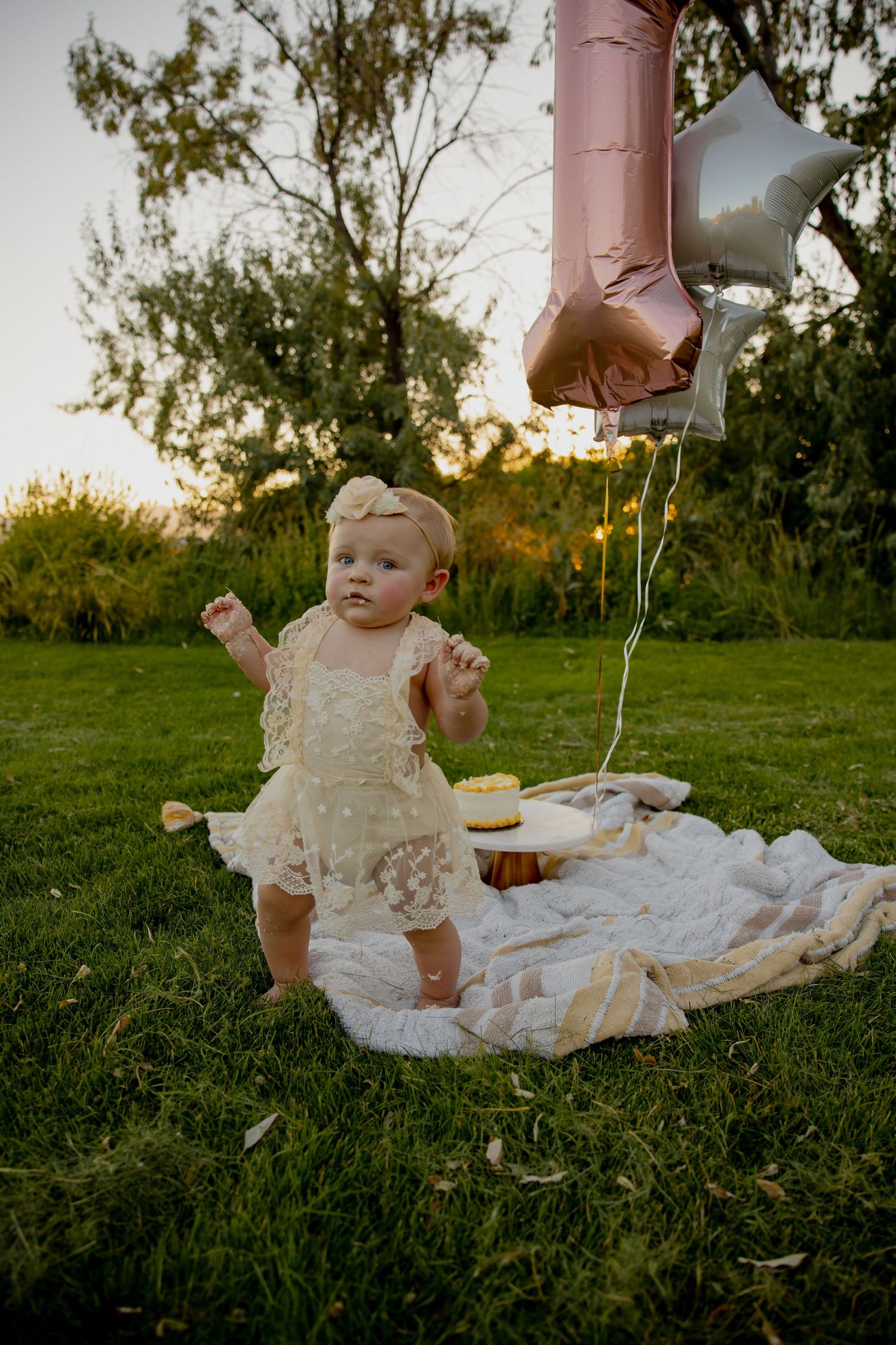 A festive outdoor celebration with pink balloons and white decorations on grass.