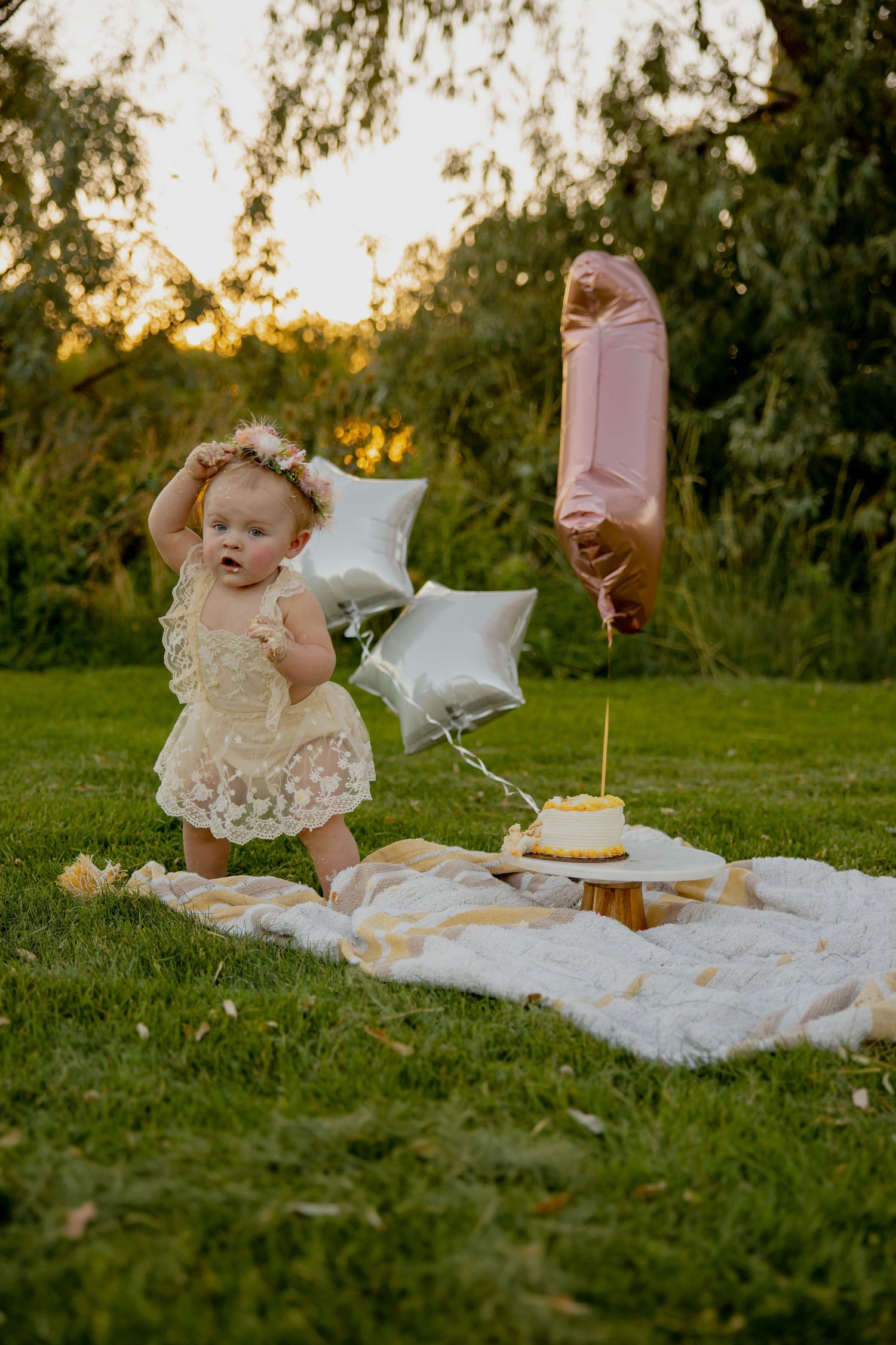Pink number balloon and silver stars float above a garden cake smash setup.
