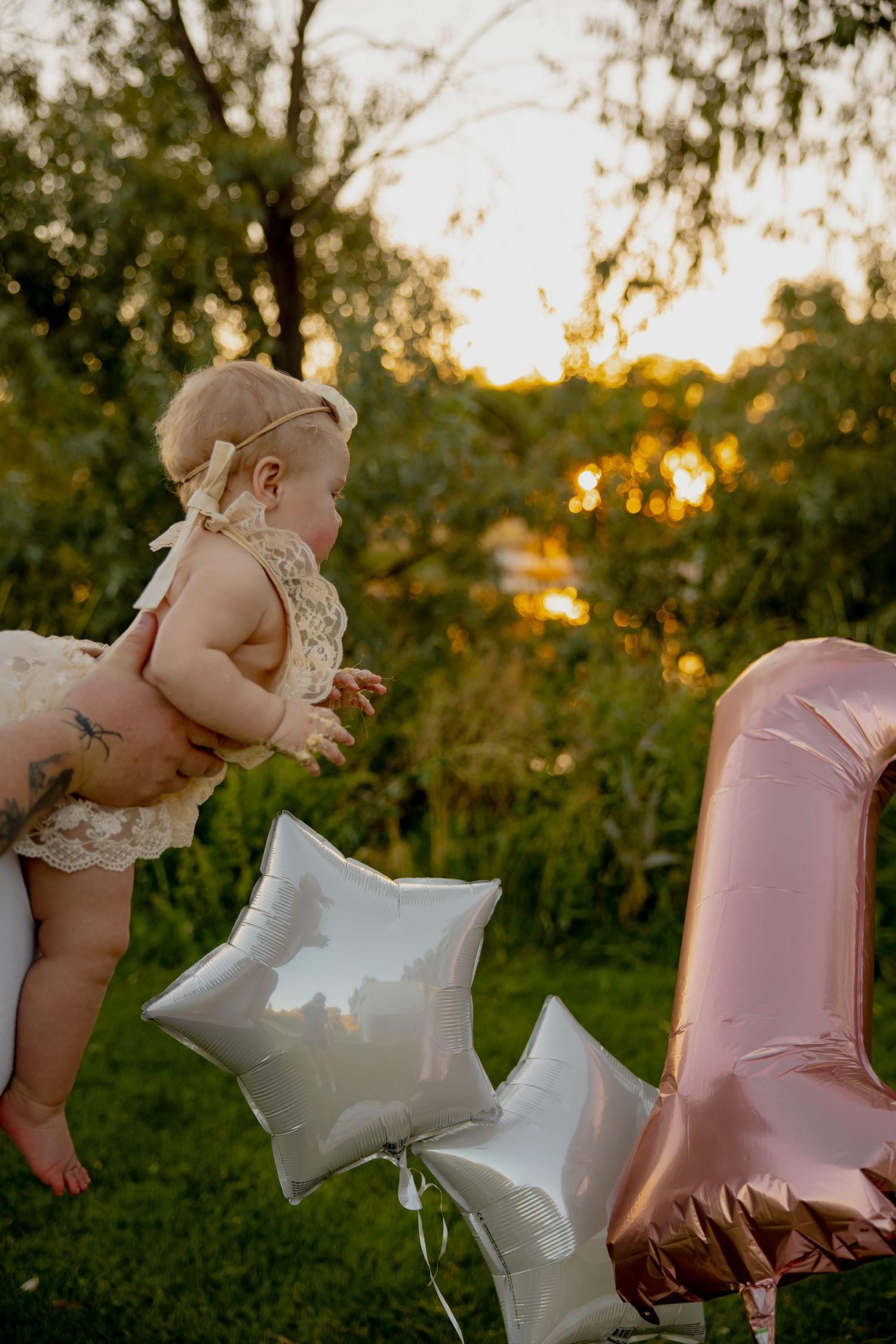 Outdoor celebration scene with pink balloons and silver stars against sunset.