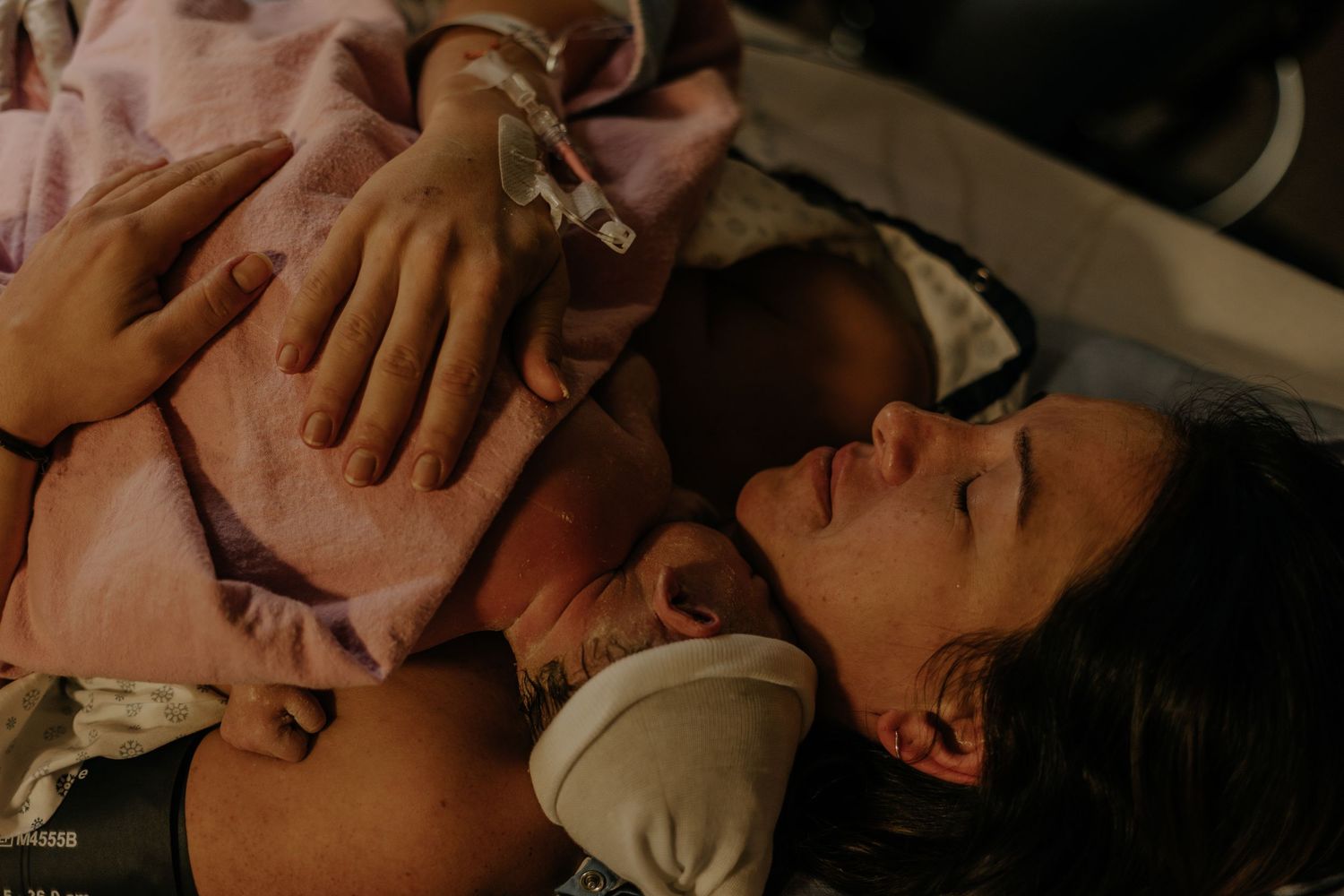 Mother with her newborn baby in the chest, minutes after giving birth, crying relieved.