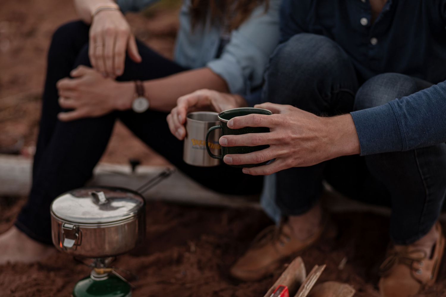 Close-up of couple holding mugs by a beach fire during a cozy cinematic couples photoshoot with Lumenali Photography. Chelton, PEI, Canada.