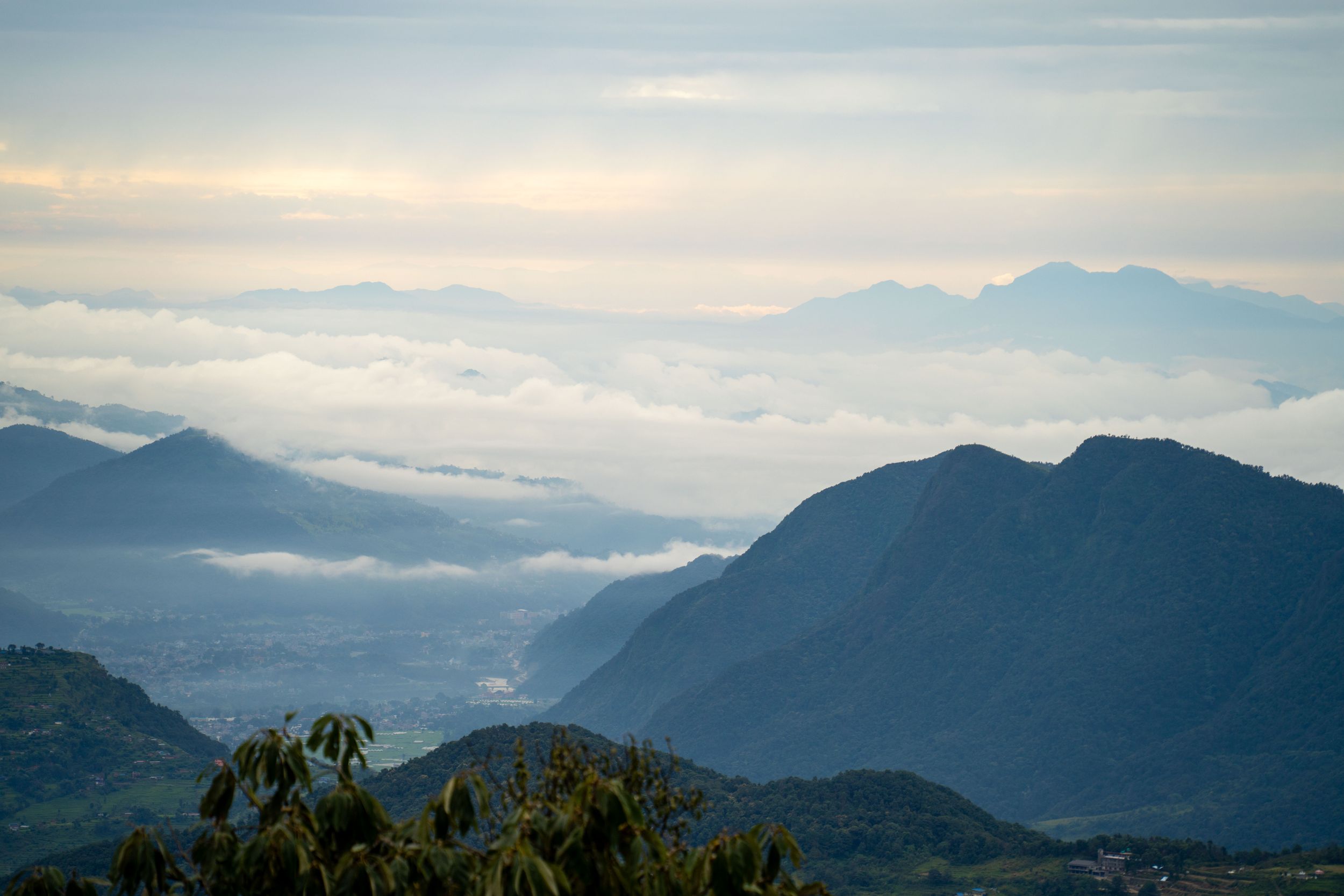 Misty mountain ranges stretching into distance under cloudy sky at high altitude.