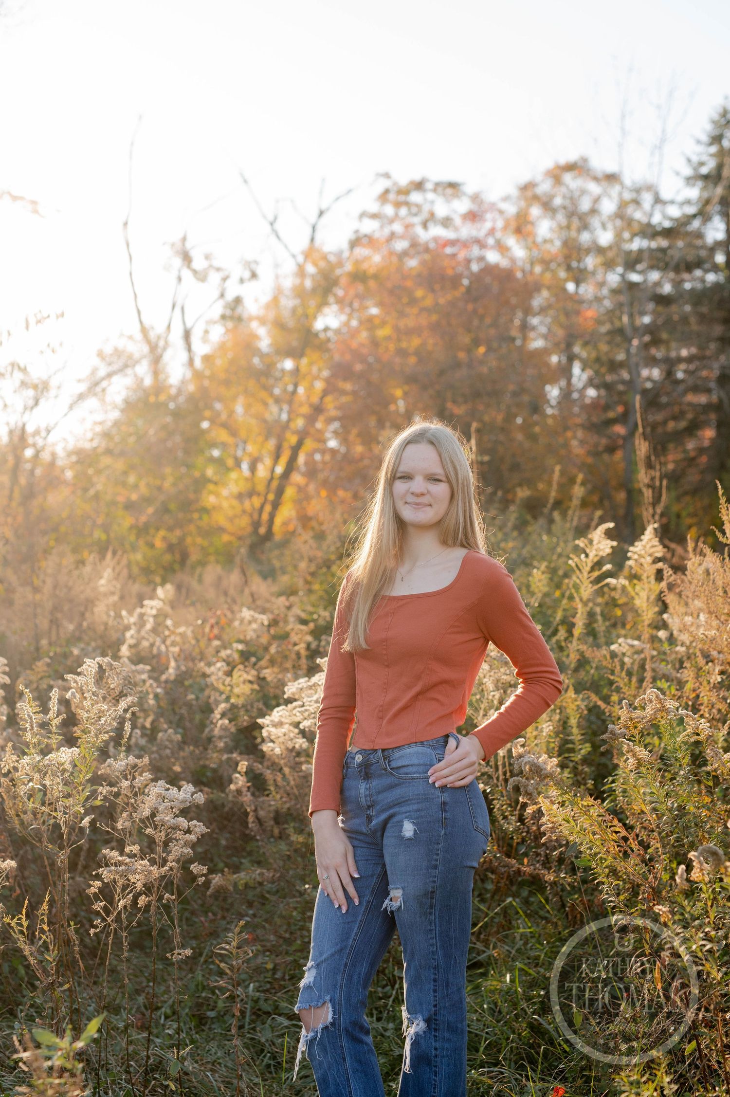 Casual portrait with orange sweater and ripped jeans in a autumn field setting.