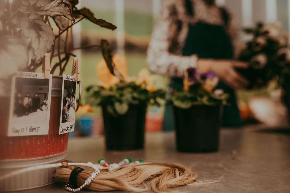 A blurred glass jar sits on a wooden surface next to potted plants in warm, atmospheric lighting.