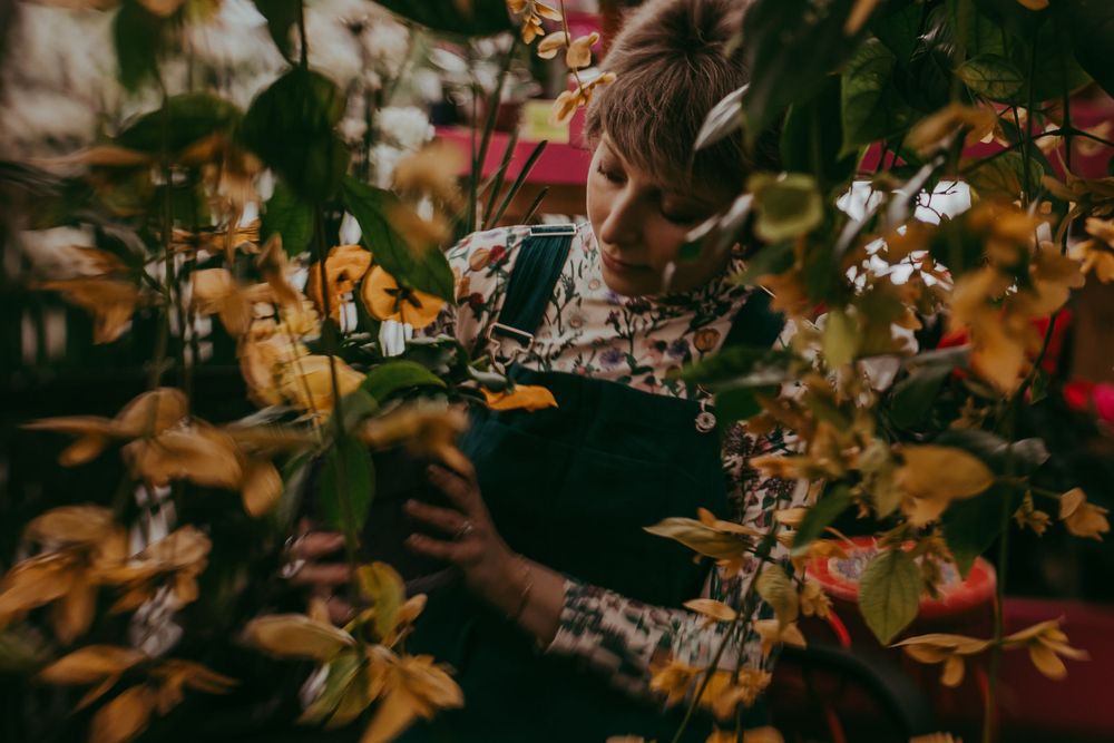 woman in overalls surrounded by yellow flowers. Whitney Popp, Popp Photography