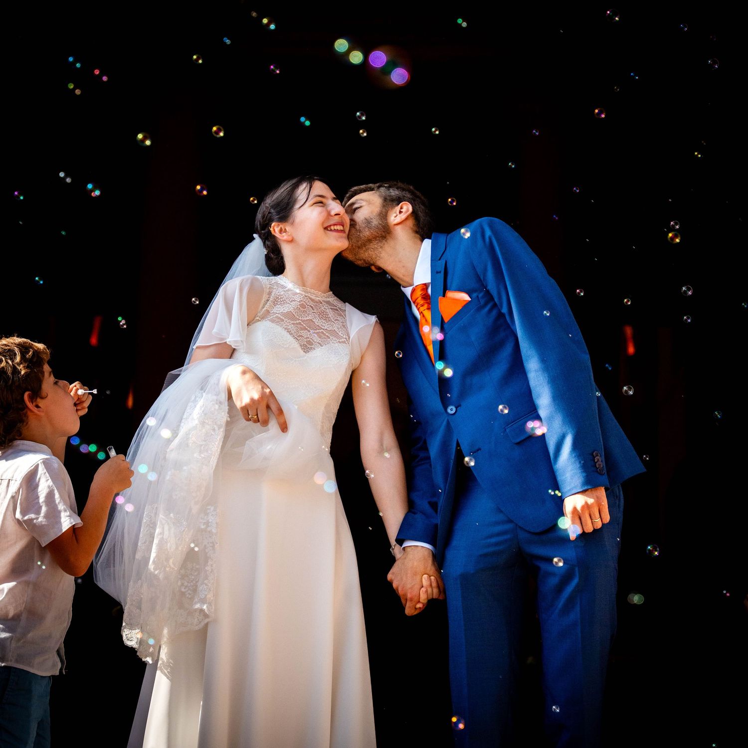 Un couple partage un moment de joie et de célébration de leur mariage alors que des confettis tombent autour d'eux à la sortie de l'église.