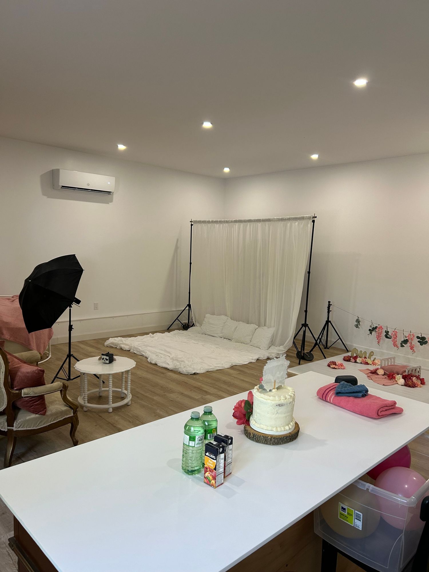 Professional photography studio setup with white backdrop, lighting equipment, and props arranged in a clean modern space.