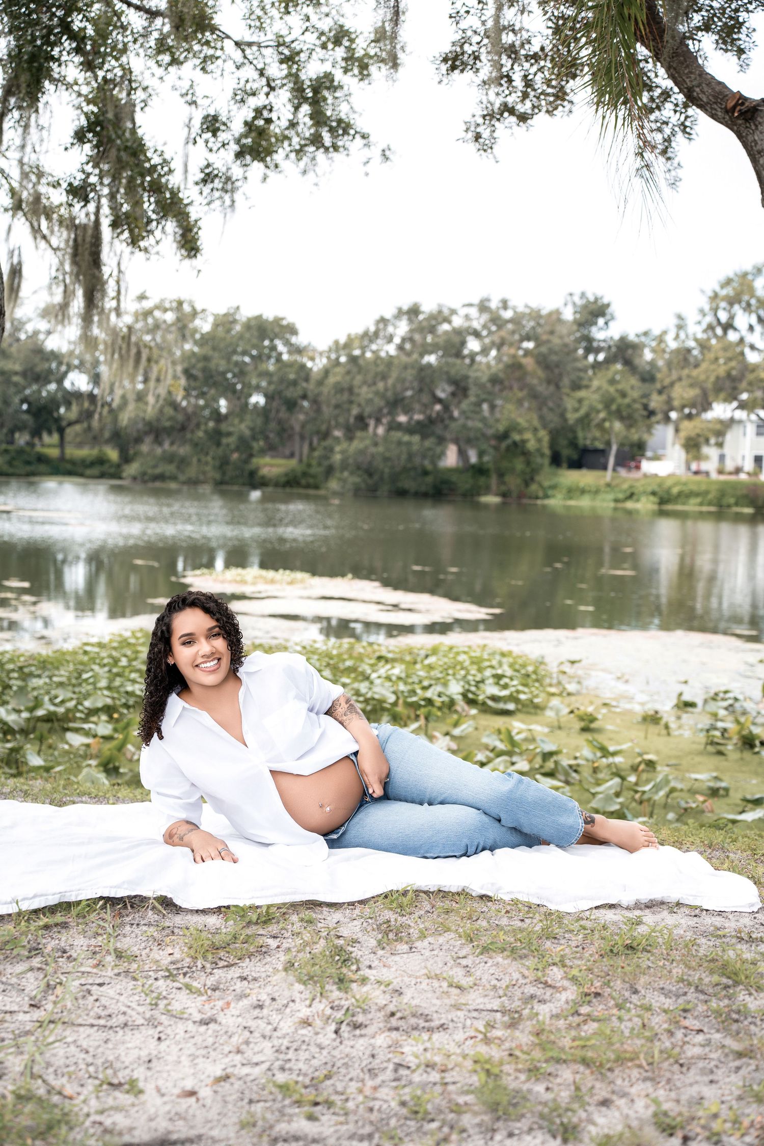 A tranquil lakeside scene with Spanish moss draped trees and white flowers dotting the shoreline.