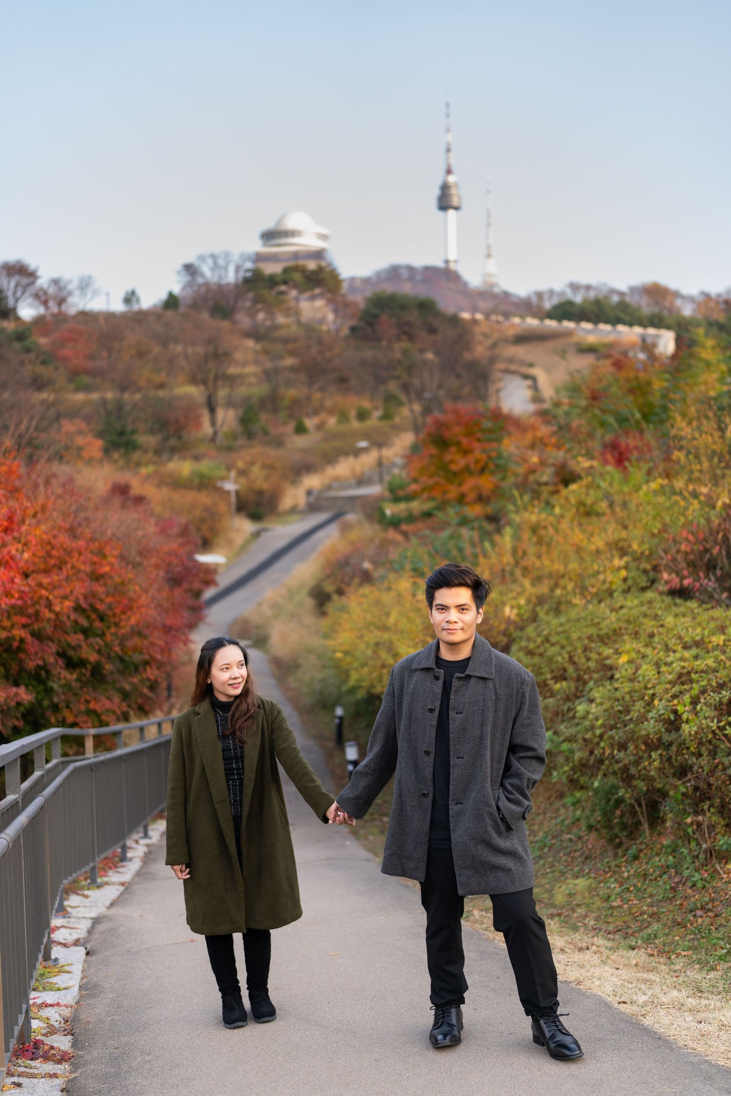 A scenic autumn path with colorful fall foliage and winding walkway leading to a hilltop observatory in Korea.