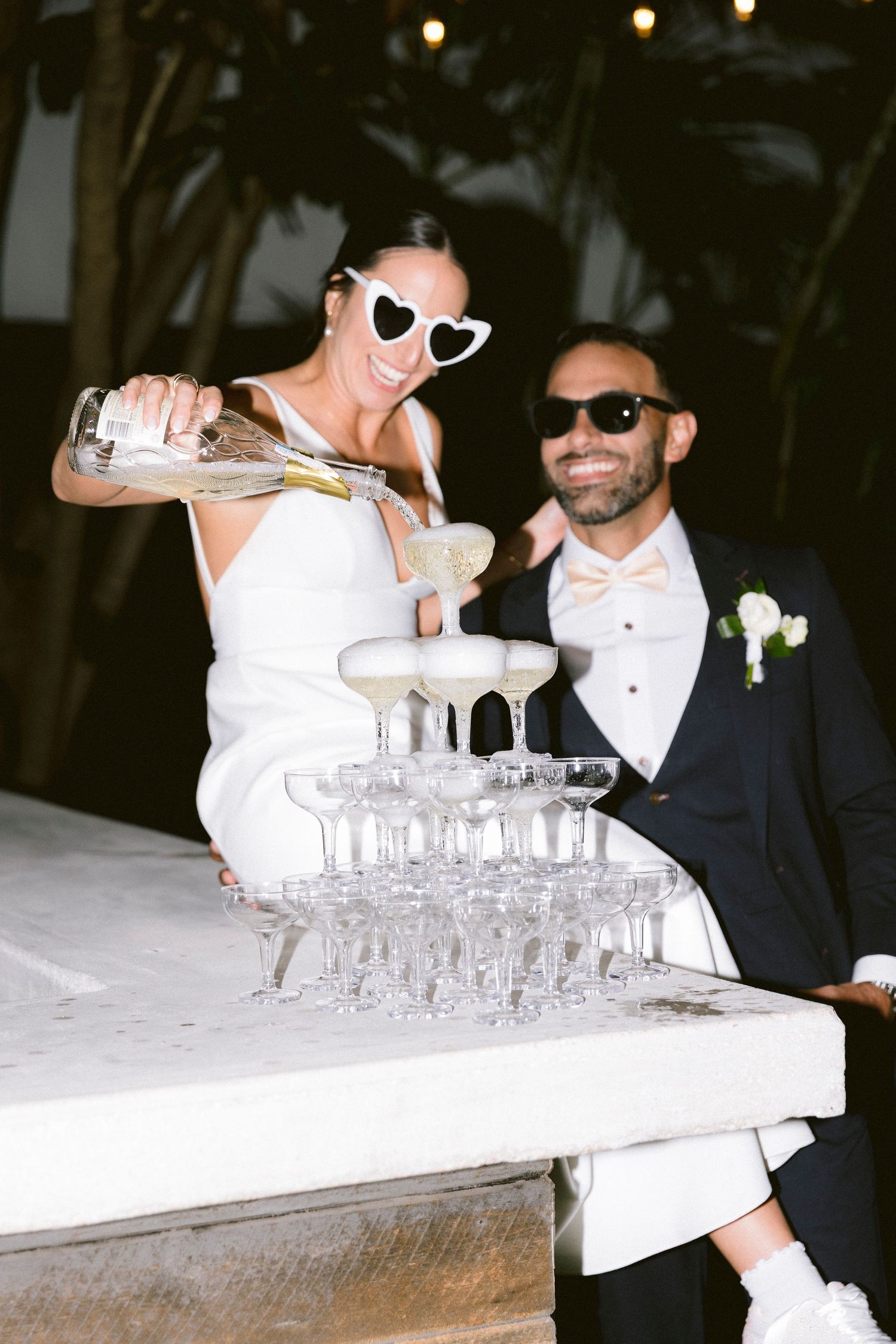 Wedding celebration with champagne tower being poured at an evening reception.