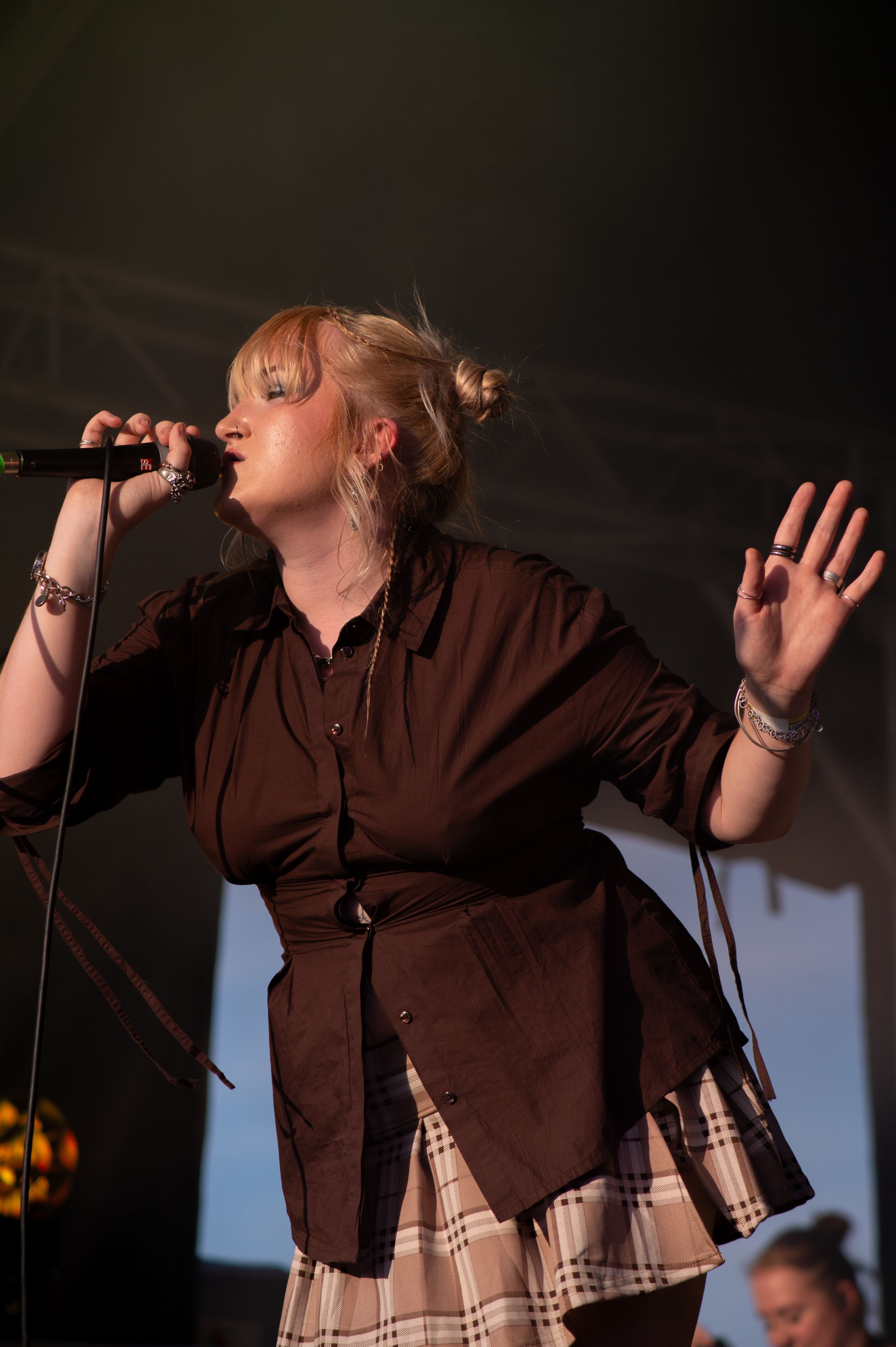 Singer performs passionately on stage wearing a brown button-down shirt during a concert performance.