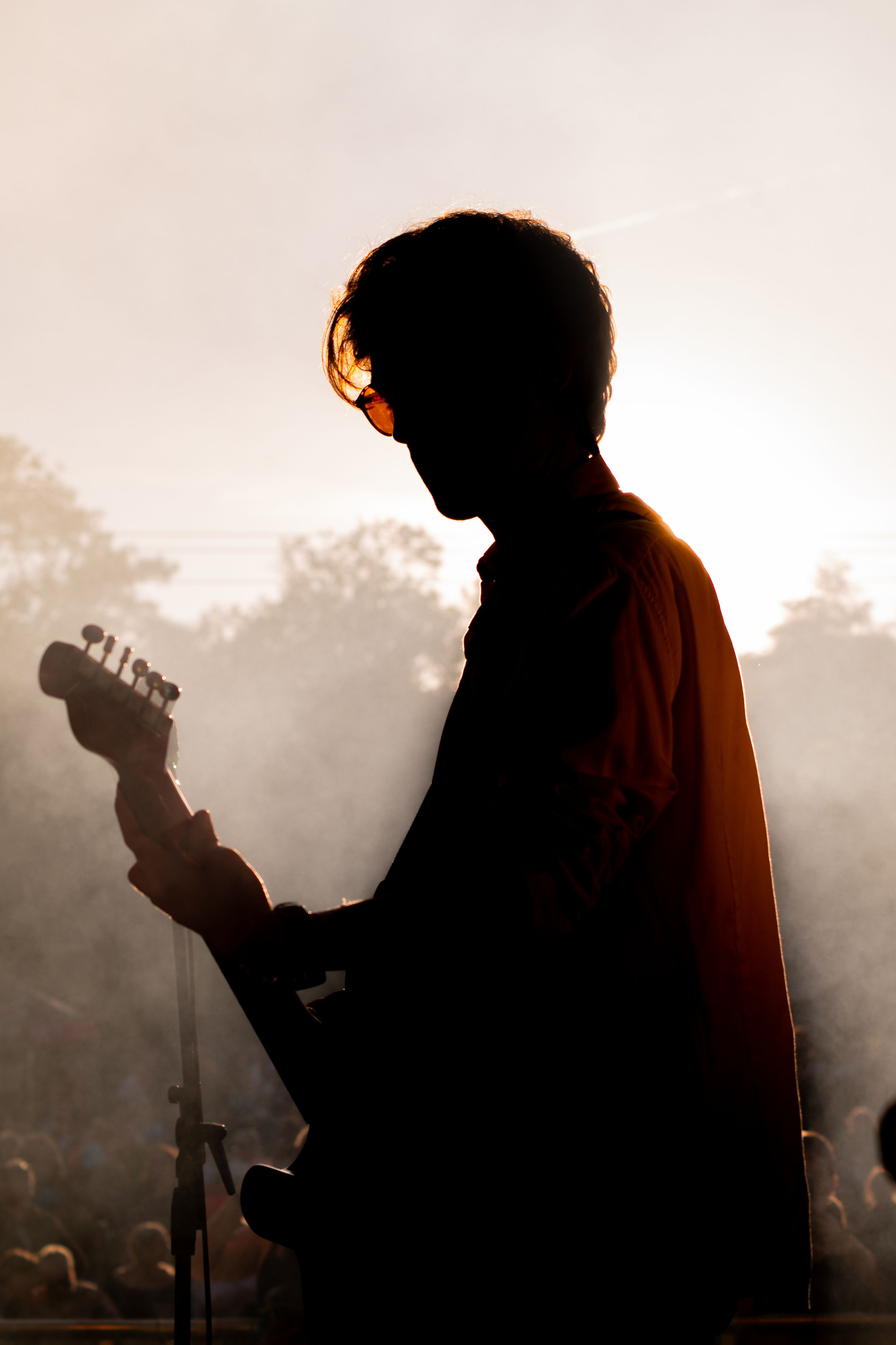 A silhouetted figure playing guitar is captured in a series of moody, backlit shots against a misty background.