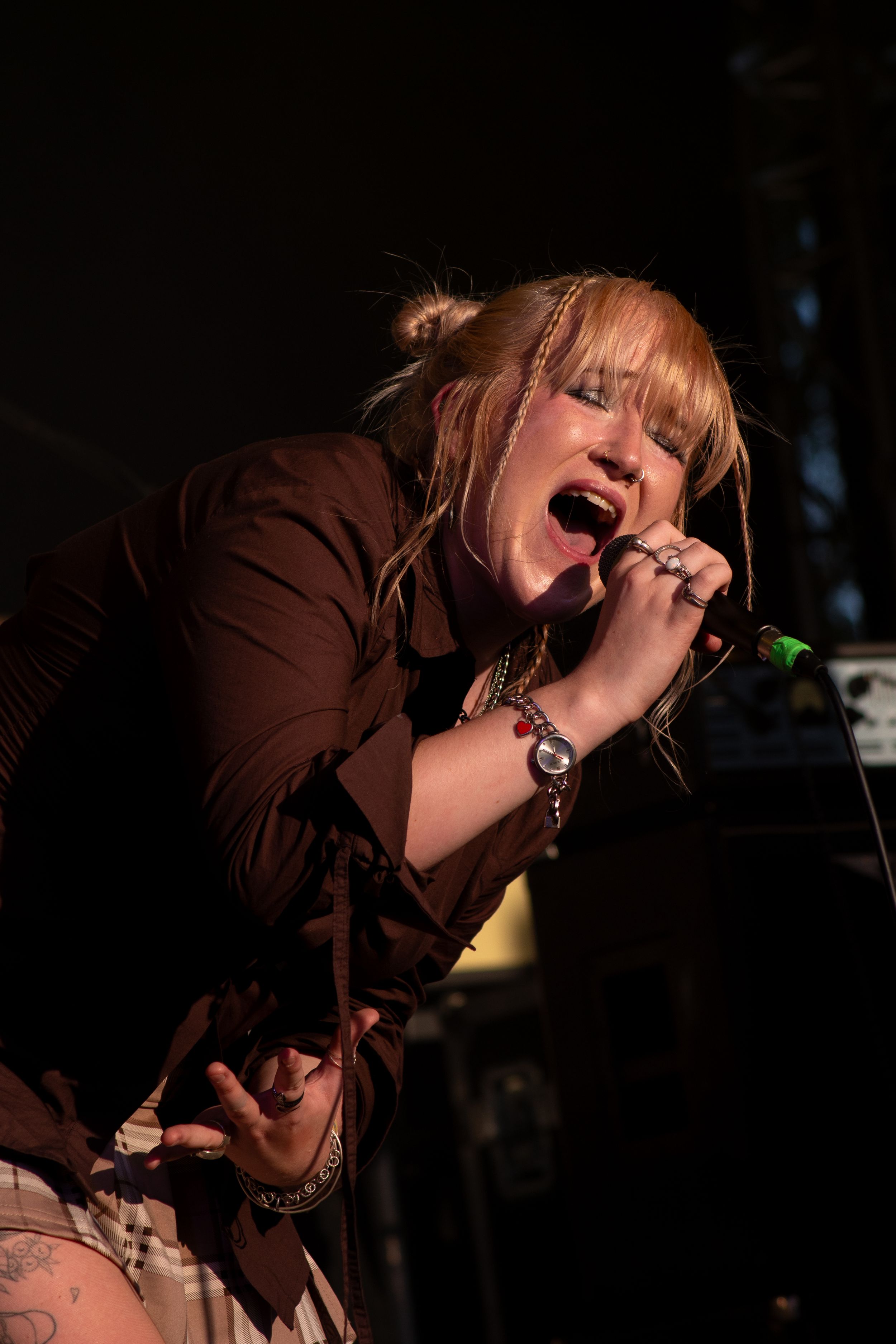 Singer performs passionately on stage in dramatic lighting while holding a microphone.