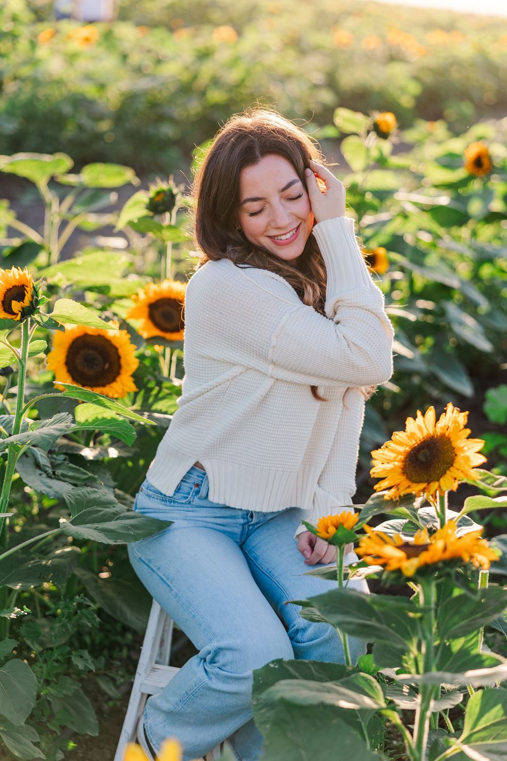 Smiling among sunflowers at Conejo Family Farms during a golden hour portrait session in Camarillo.