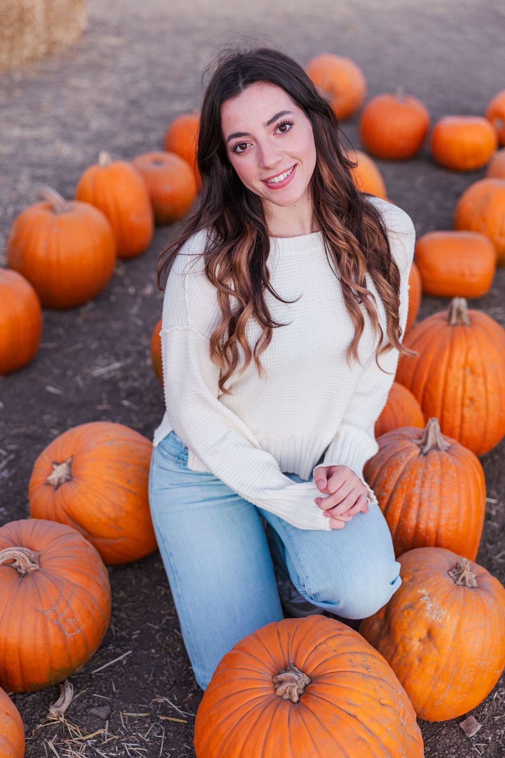 A cozy autumn scene with bright orange pumpkins scattered on the ground at a pumpkin patch.