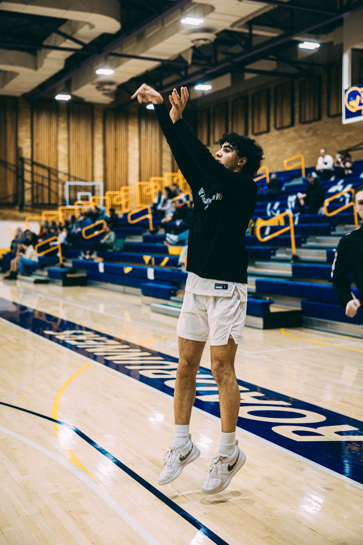 Basketball player in motion on shiny court with blue and yellow team colors visible.