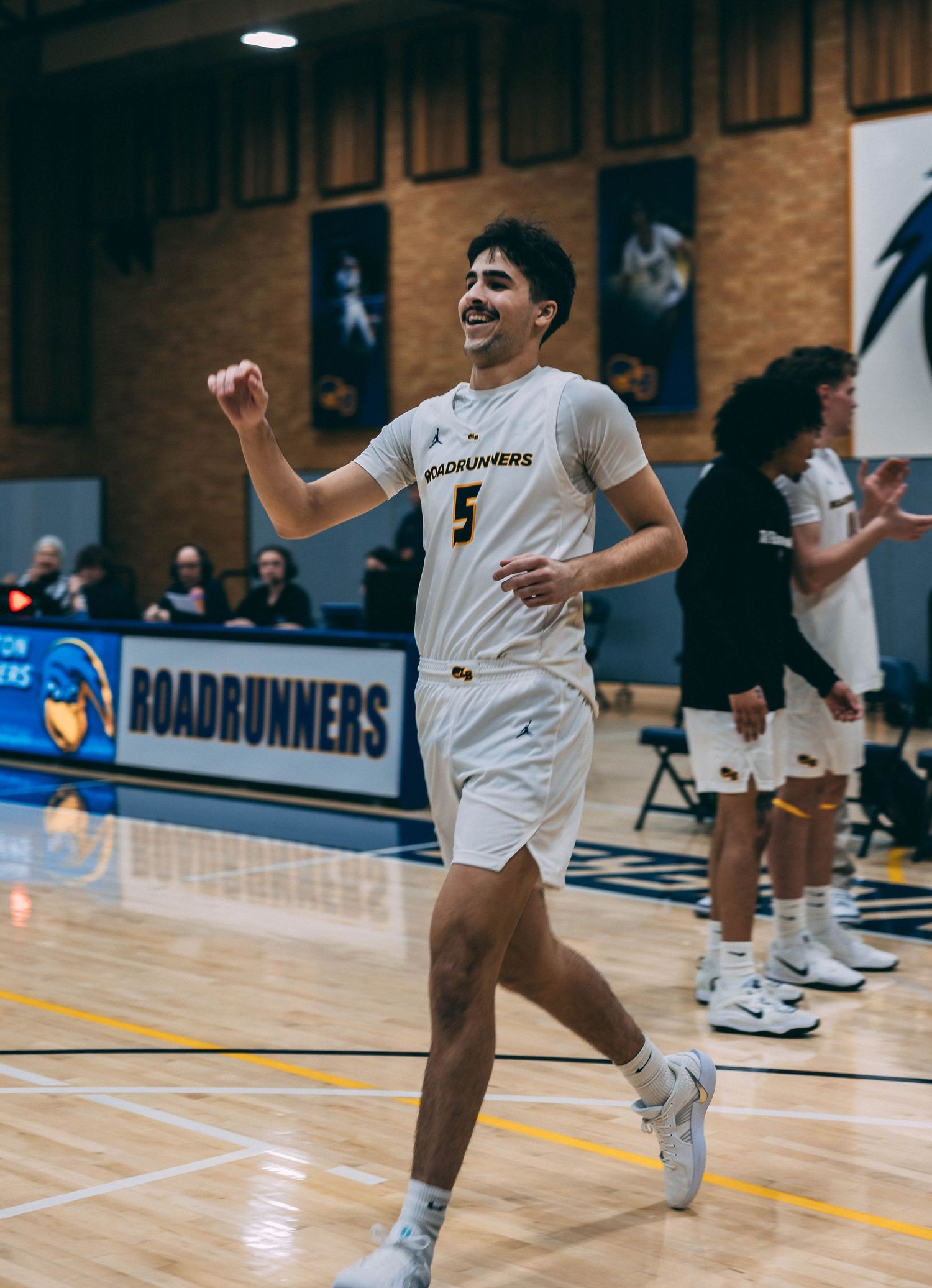Player in white uniform celebrates during basketball game on indoor court.