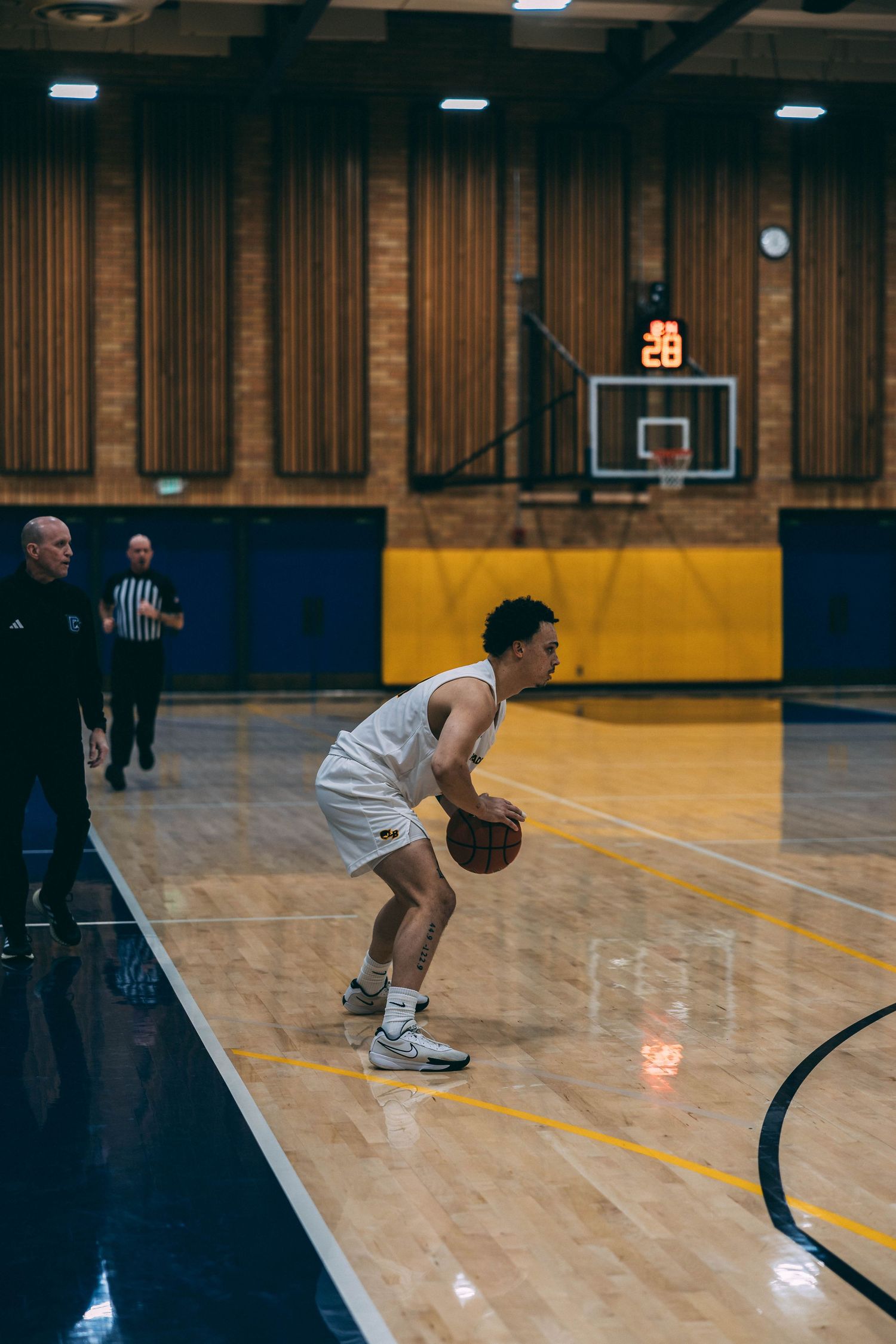 Basketball player crouches in defensive position during practice on polished court.