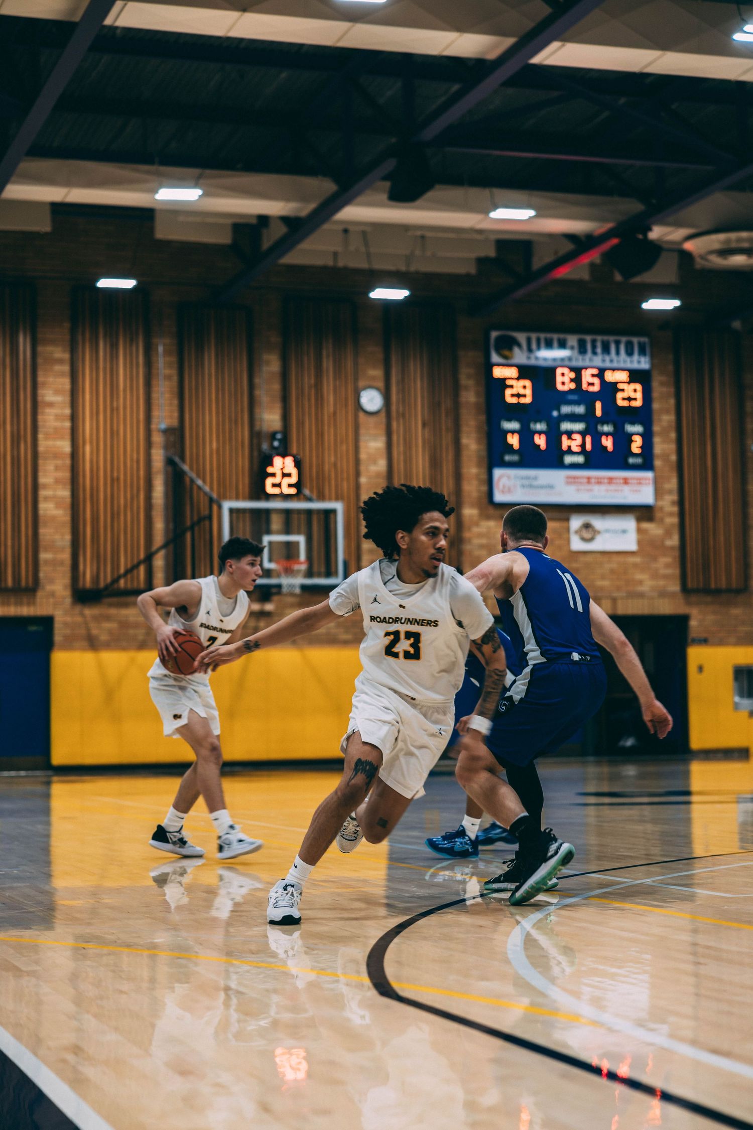 Basketball players diving and scrambling for a loose ball during competitive game play.