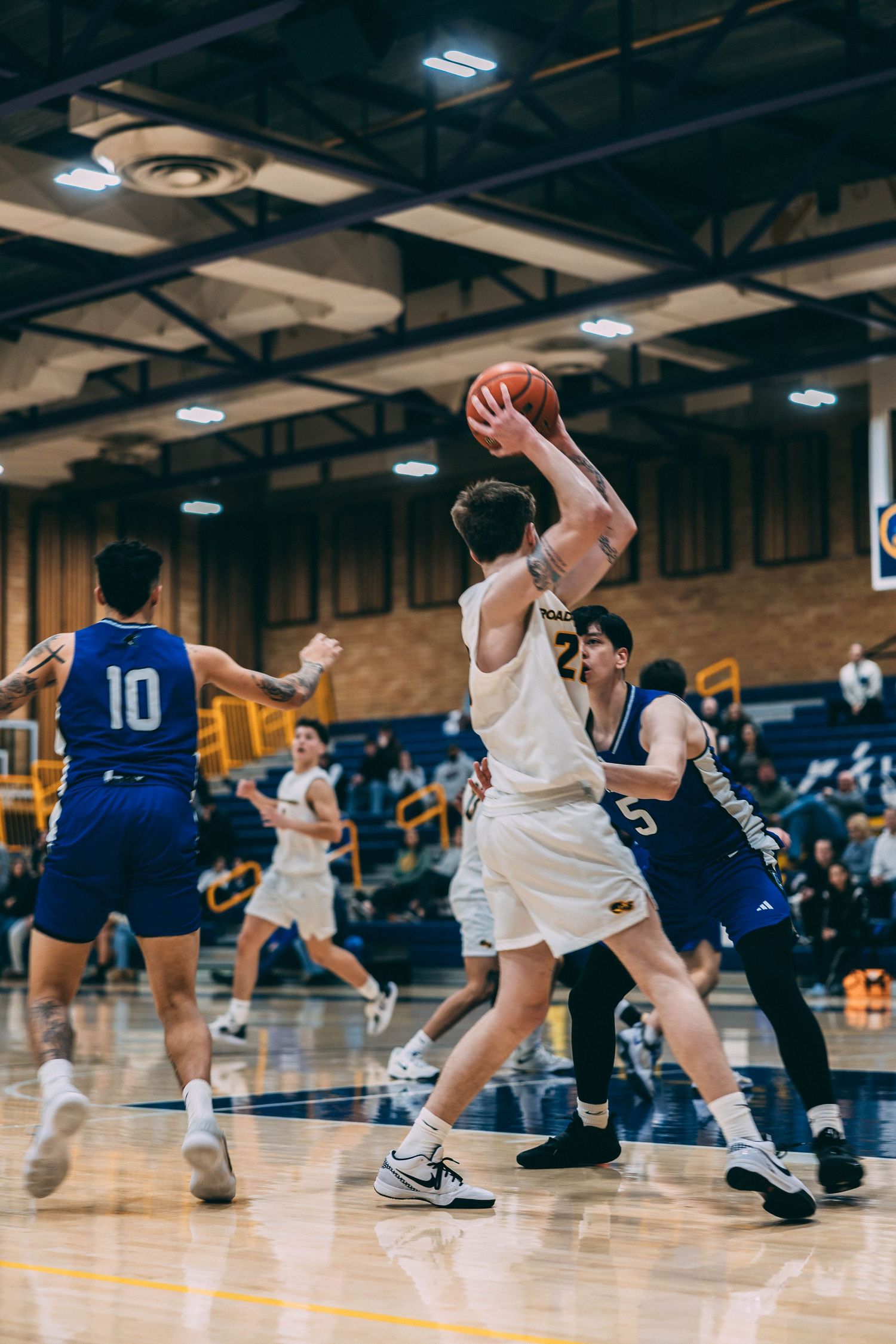 Players in white and blue uniforms battling for position during basketball game.