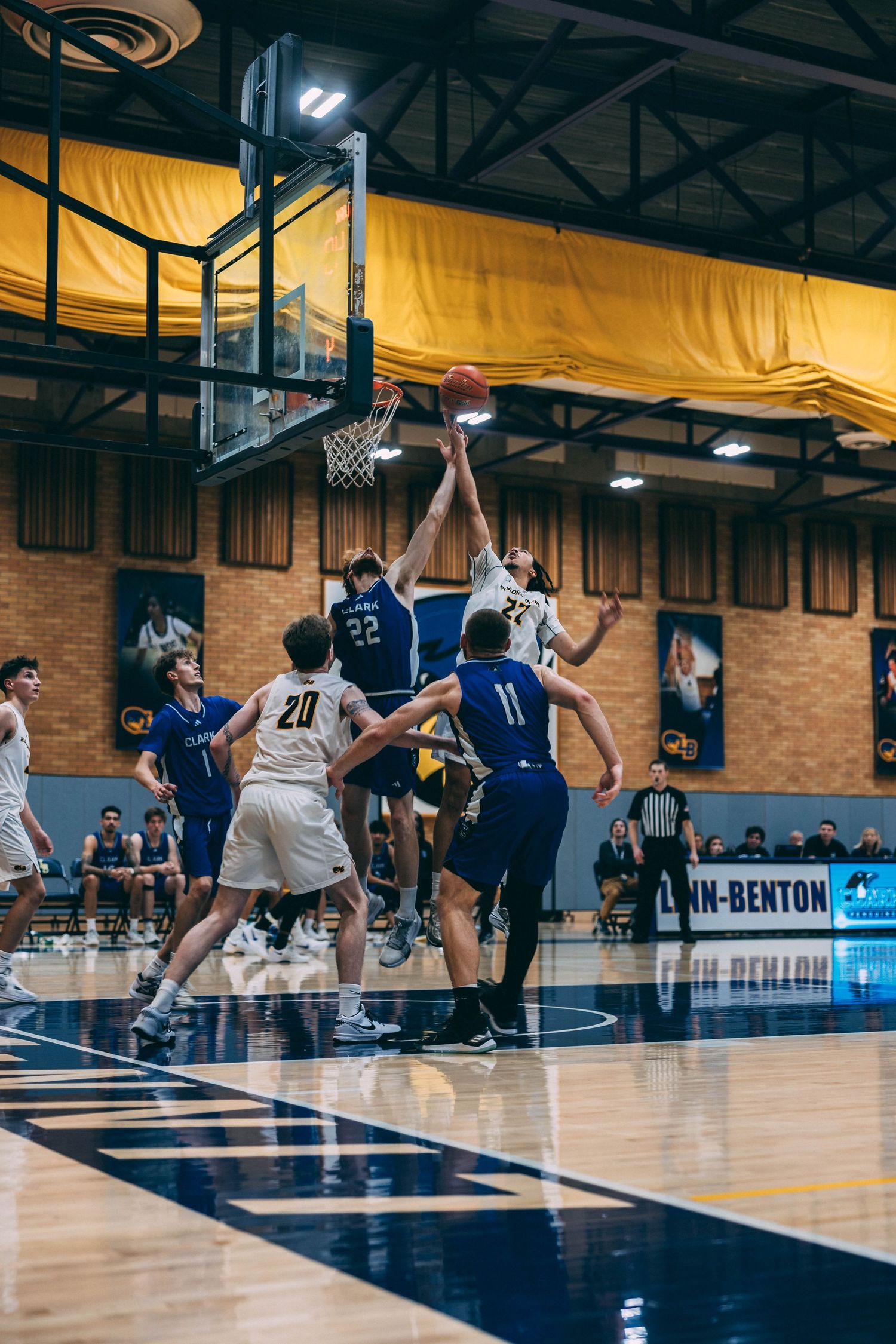 Basketball players battling under the hoop during competitive game action.
