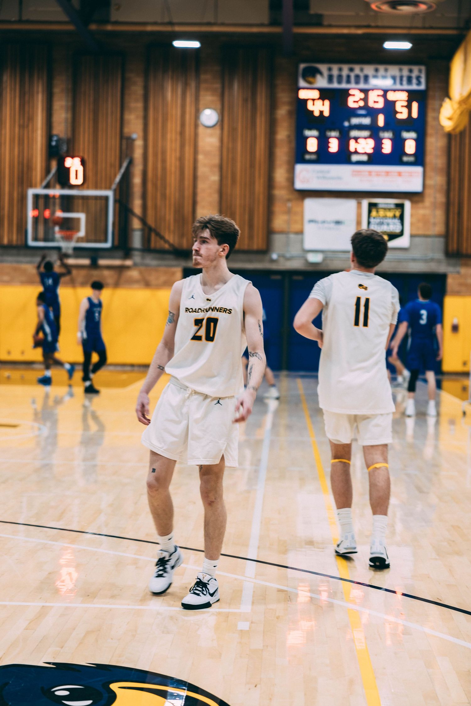 Basketball players in white uniforms spread out across the court during a game.