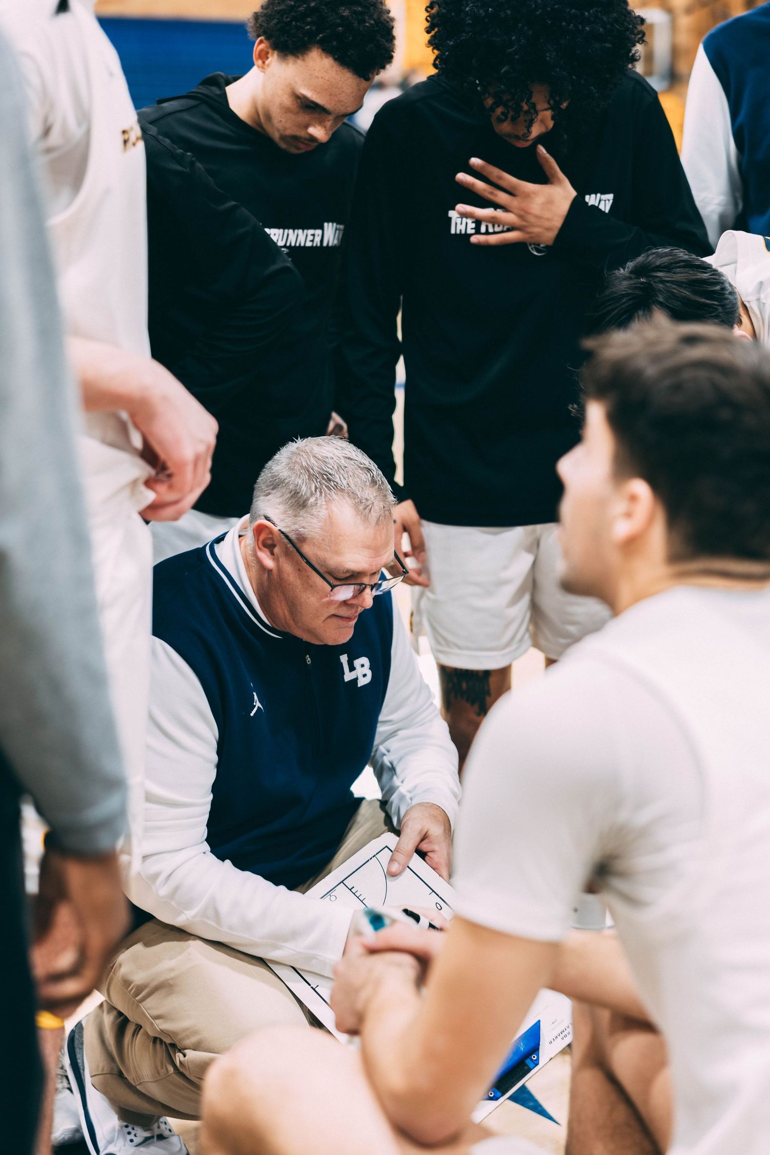 Coach reviews game strategy with team during a basketball timeout.
