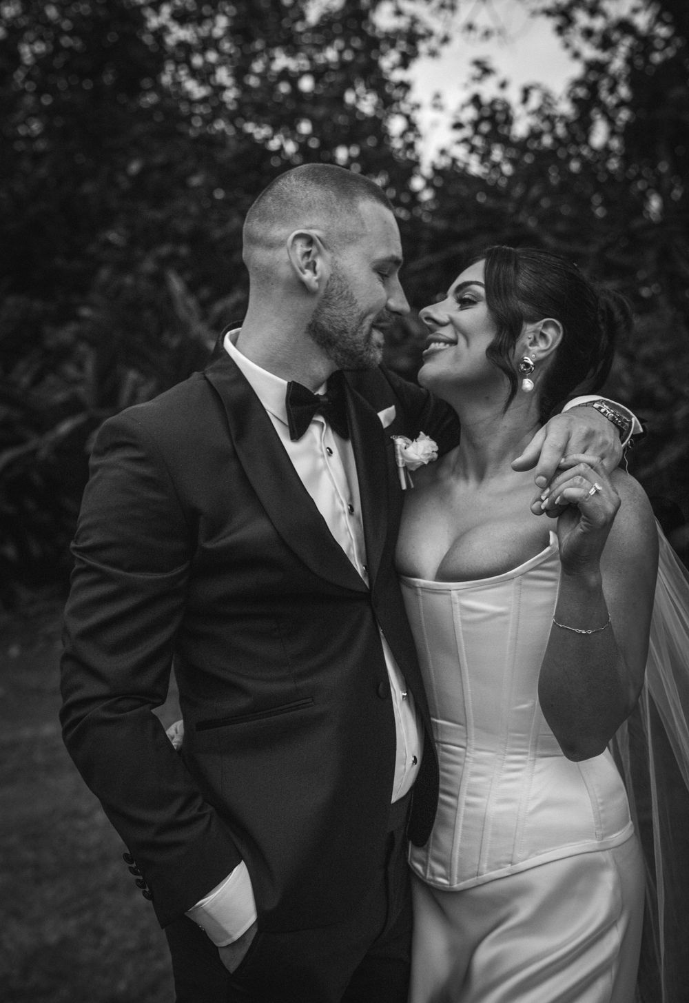 Black and white candid wedding photo showing intimate moments between newlyweds and wedding party members.