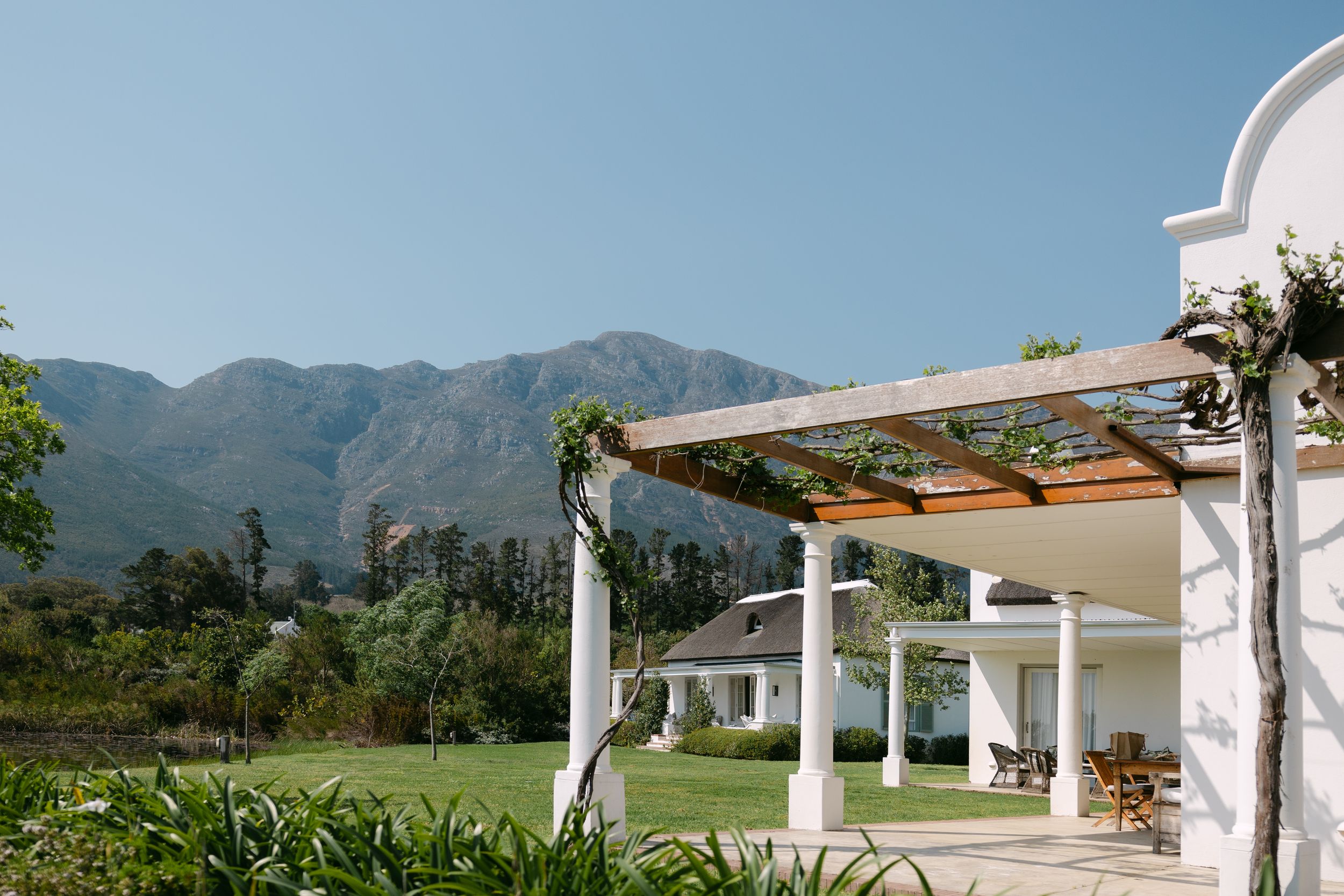 Modern white pergola structures create an elegant outdoor seating area against a backdrop of mountain scenery.