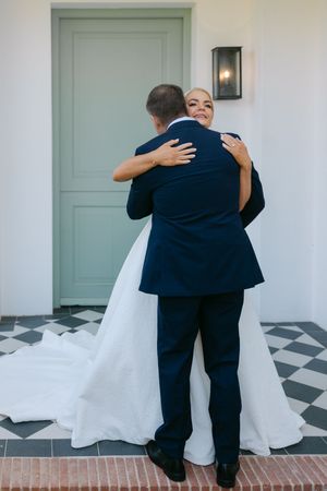 Emotional wedding moment captured in a series showing an embrace in front of a mint green door.