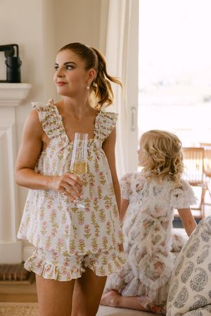 Group dancing in floral white dresses with ruffled details in a bright indoor setting.