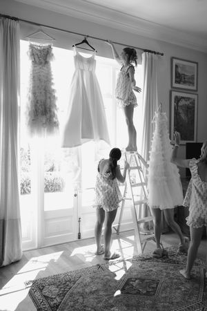 Silhouettes of people preparing wedding dresses against bright windows.