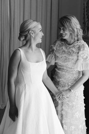 A sequence of black and white photos showing two people in elegant white dresses interacting and laughing together.